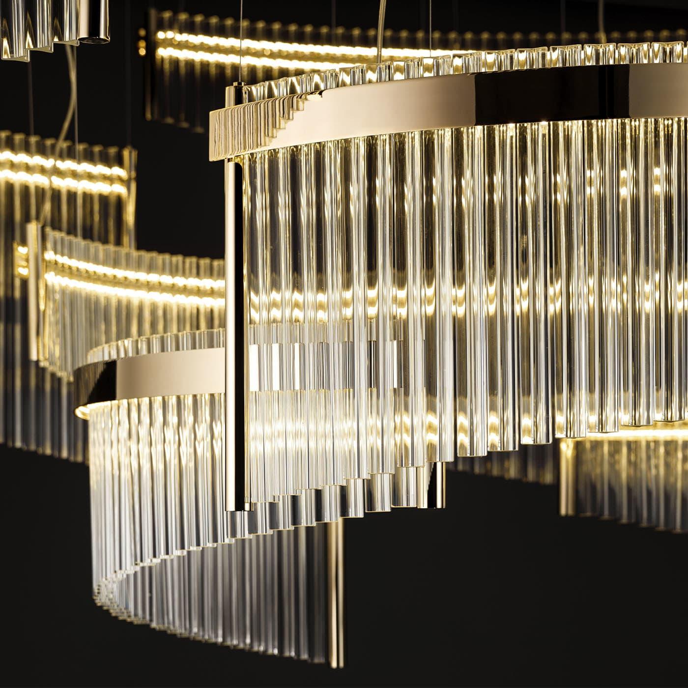 At once sculptural and ethereal, this chandelier boasts a hypnotizing design where golden metal profiles combine with prized transparent Murano glass panels. The dynamism stated by the glass elements' curved shape is maximized by their distinctive