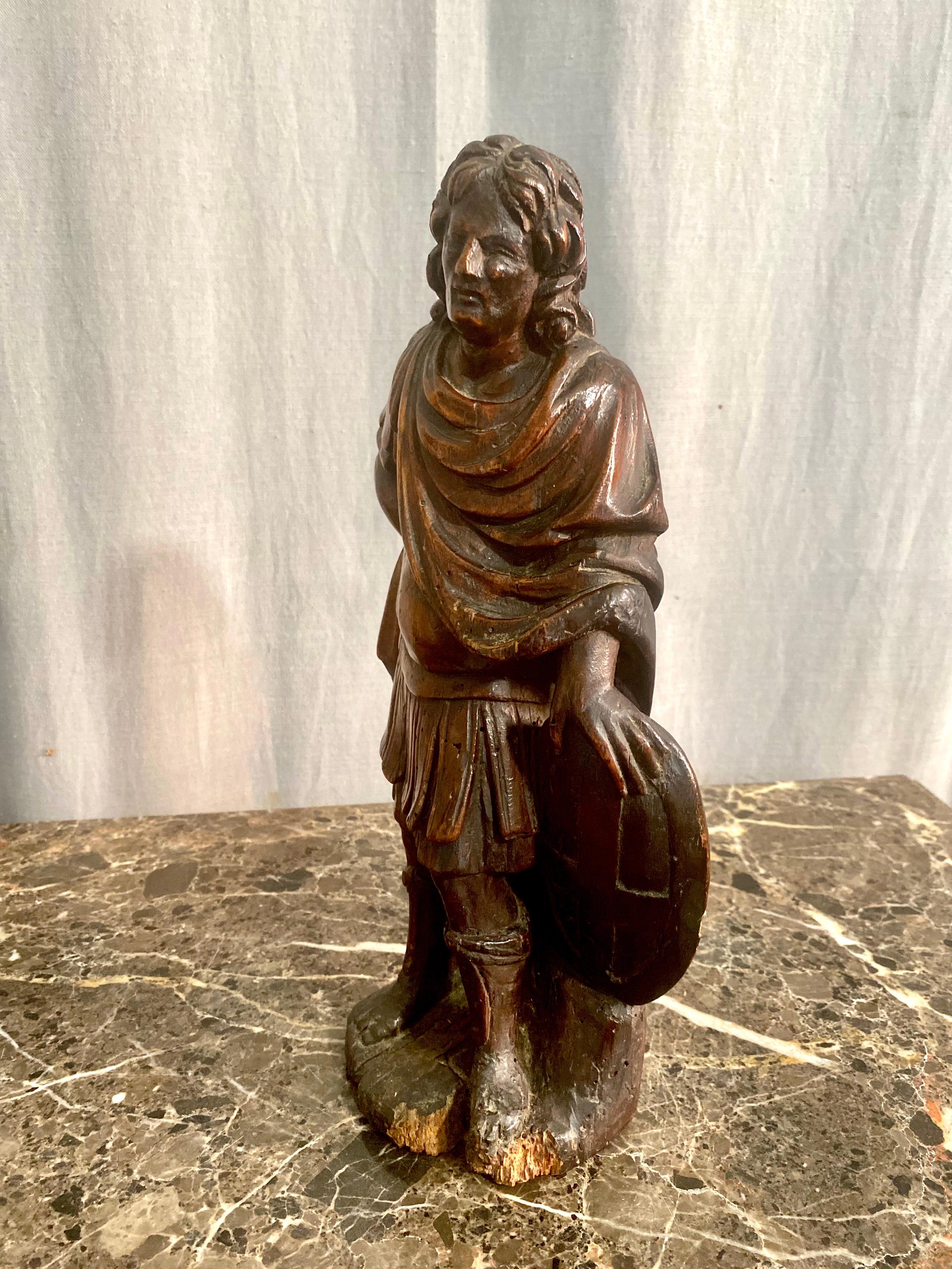 Splendida statua antica in legno intagliato raffigurante Sant'Adriano, vestito da soldato romano e con in mano uno scudo rotondo, suo attributo distintivo. Ai suoi piedi, un leone ricorda l'episodio del suo martirio, simbolo del coraggio e della