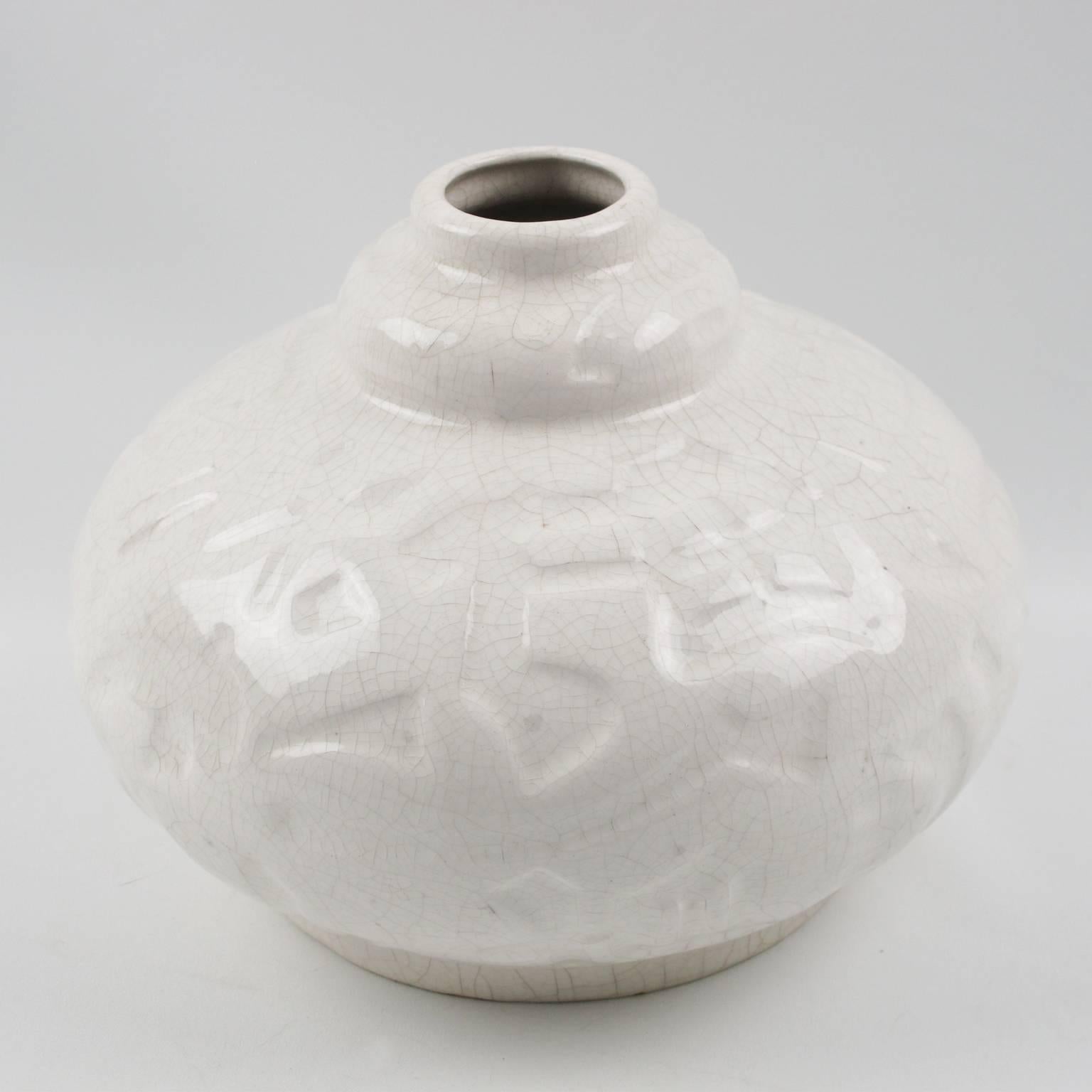 Impressive Art Deco vase by Saint-Clement, France. Lovely ceramic vase with white crackle glaze finish, featuring a large puffy round shape with small collar opening and detailed carved stylized geometric design all around. No marking