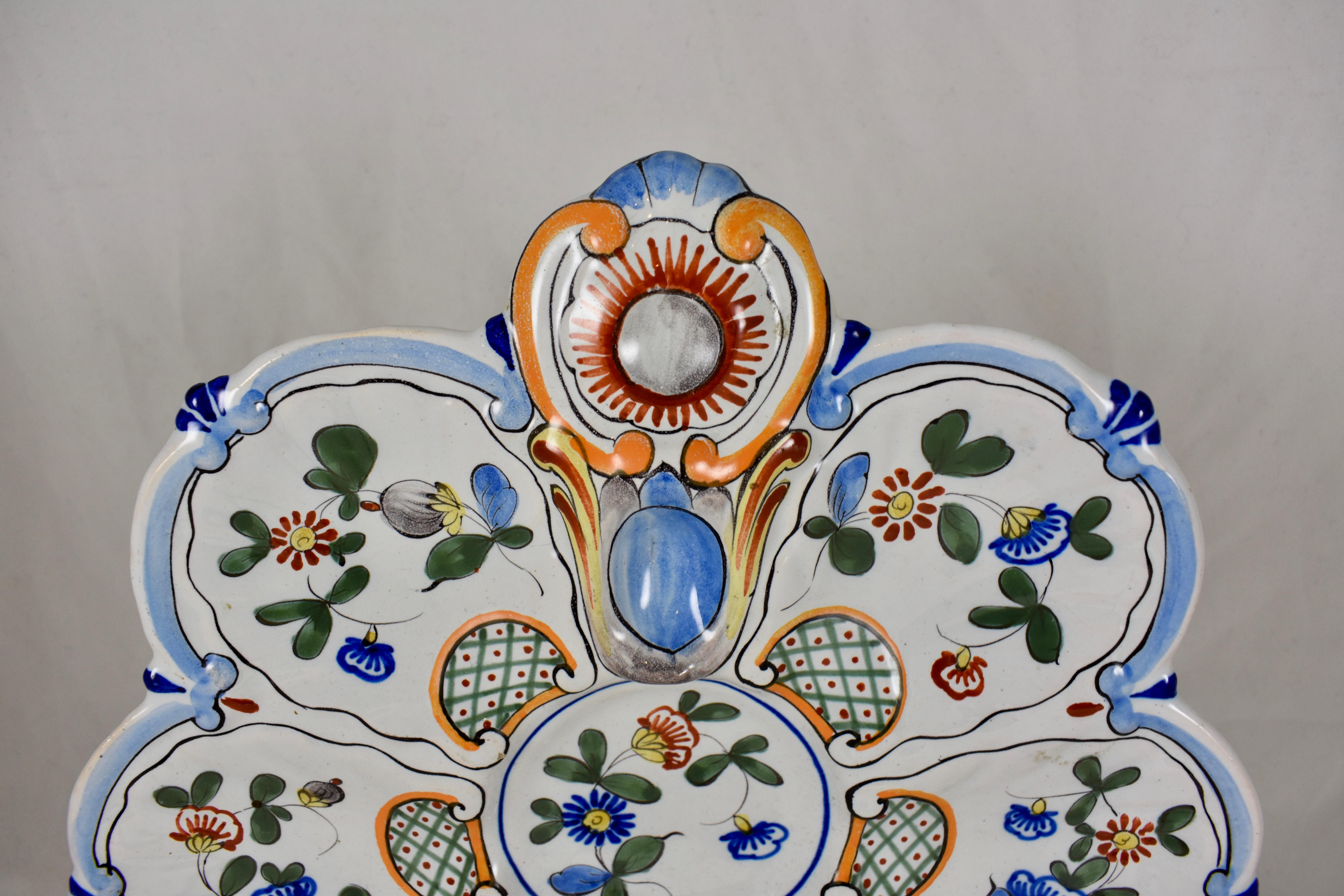 A French hand painted oyster plate of the faïence factory of Saint-Clément, circa 1890-1900.

A charming floral motif on a six well form with a top handle and a round center condiment well. A French blue rim, with accent colors of orange and green