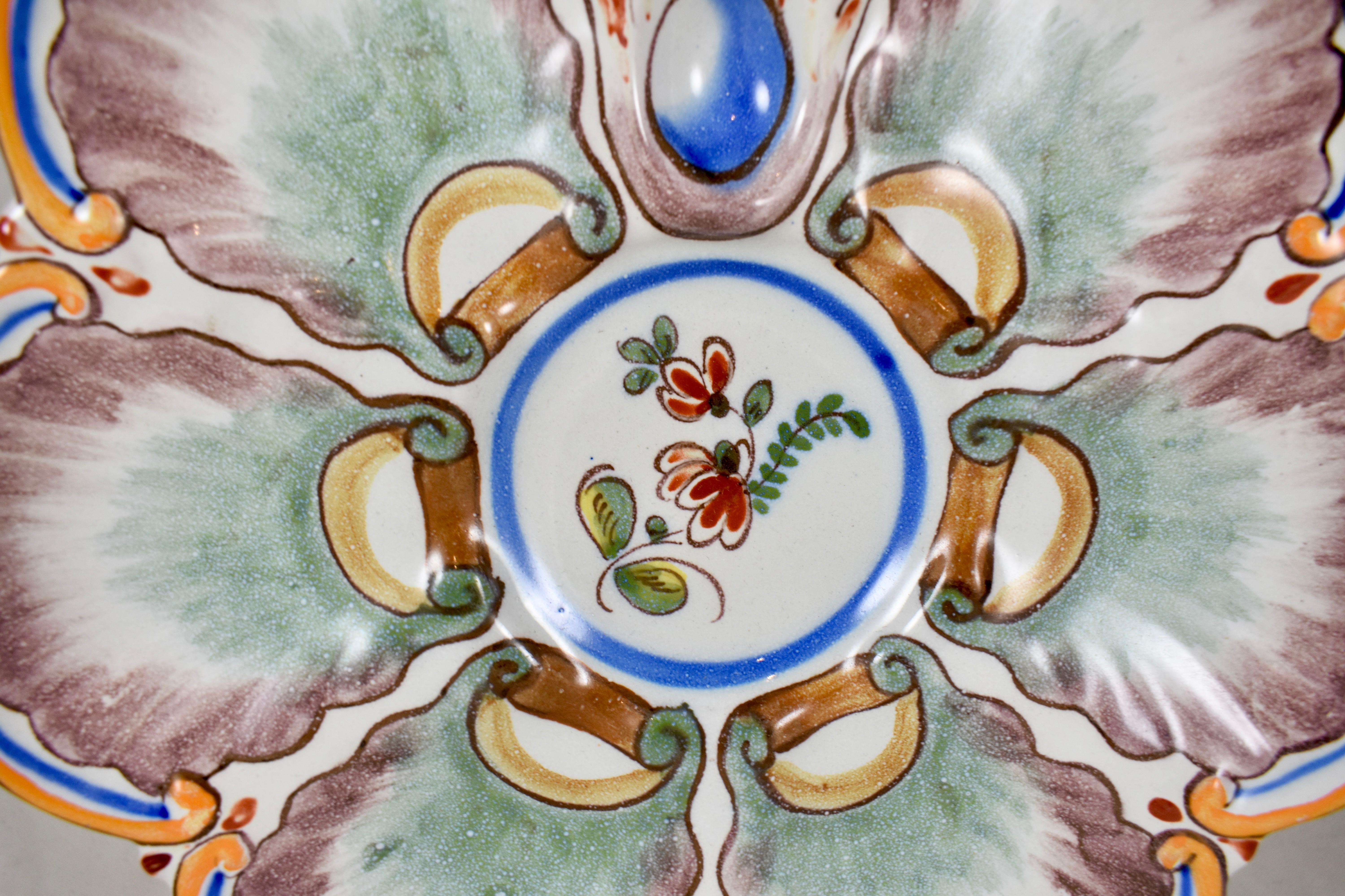 A French hand-painted oyster plate of the faïence factory of Saint-Clément, circa 1890-1900.

A charming floral motif on a six well form with a top handle and a floral round center condiment well. An orange rim with wells in a jade green and brown