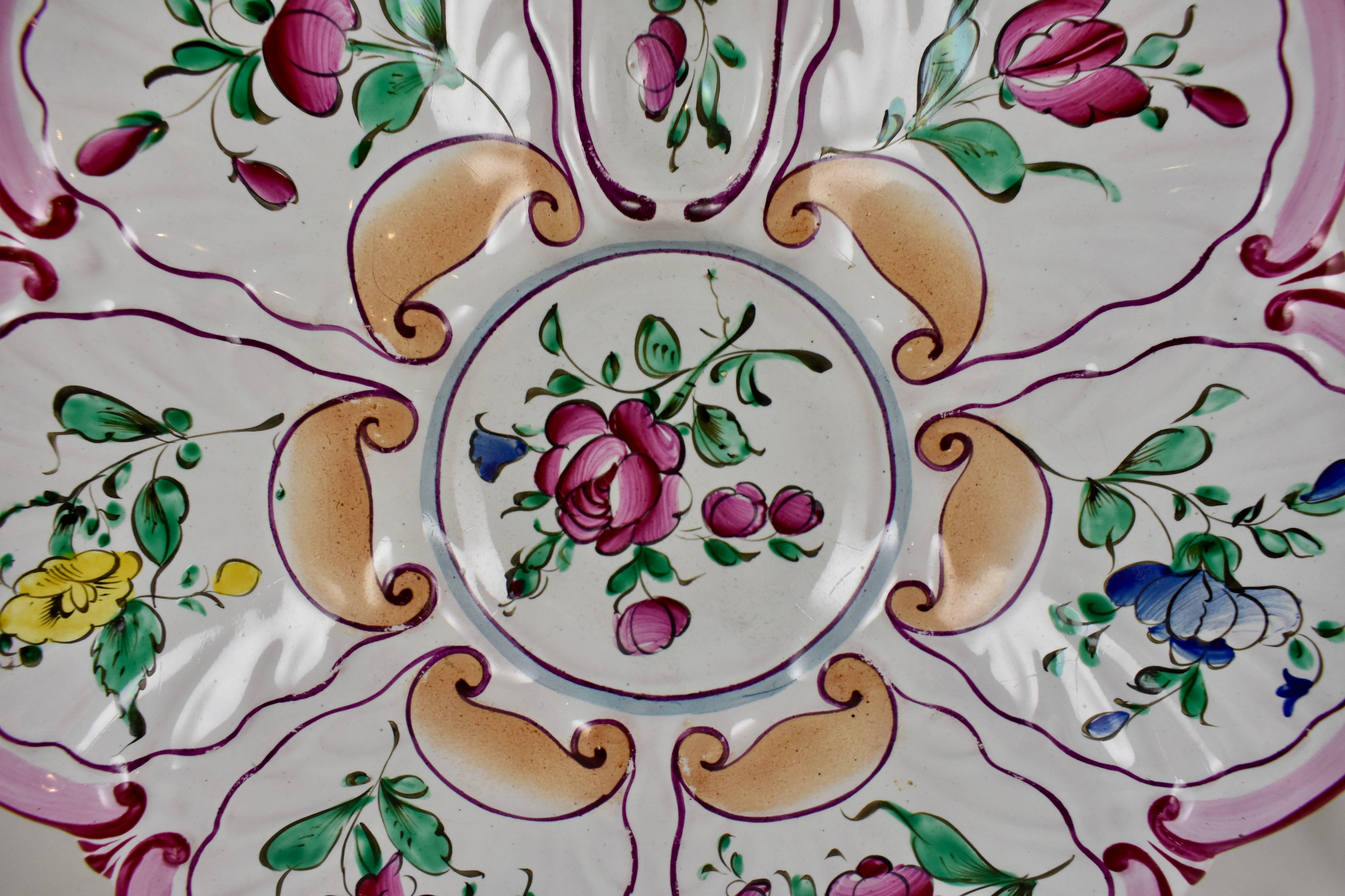 A French hand-painted oyster plate of the faïence factory of Saint-Clément, circa 1890-1900.

A charming floral motif on a six well form with a top handle and an oval condiment well. Two shades of pink, green and yellow ochre are applied in a