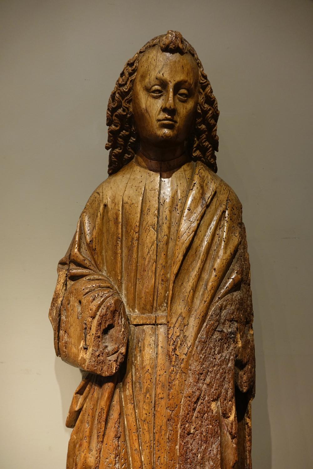 Große runde Skulptur aus Nussbaumholz, die den heiligen Johannes in der Position darstellt, die er normalerweise zu Füßen von Christus am Kreuz einnimmt.
Ein wunderschönes, ausdrucksstarkes Gesicht, umrahmt von gekonnt gelocktem Haar.
Sichtbare