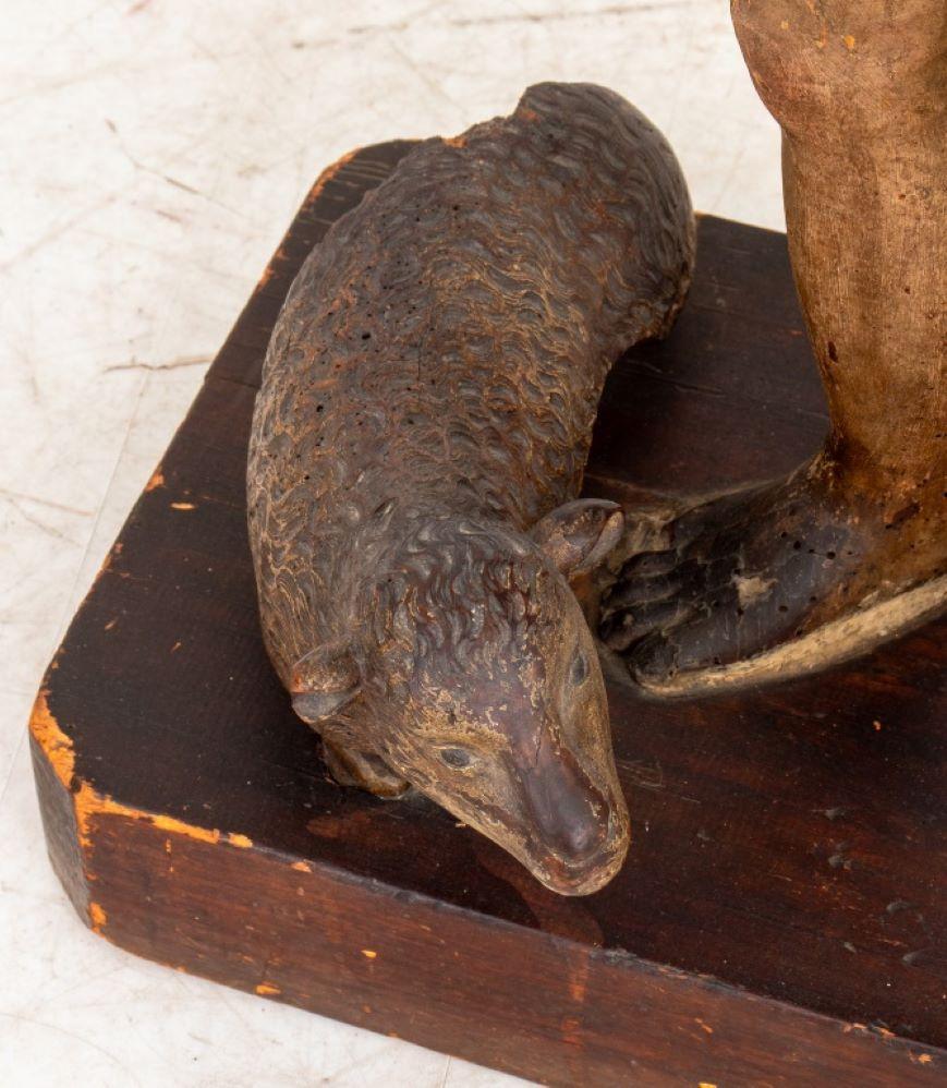 Scultura in legno scolpito e policromato di Saint Johns, inizio XIX secolo, con in mano un rotolo e accompagnato da un agnello seduto, su base rettangolare. 44,5