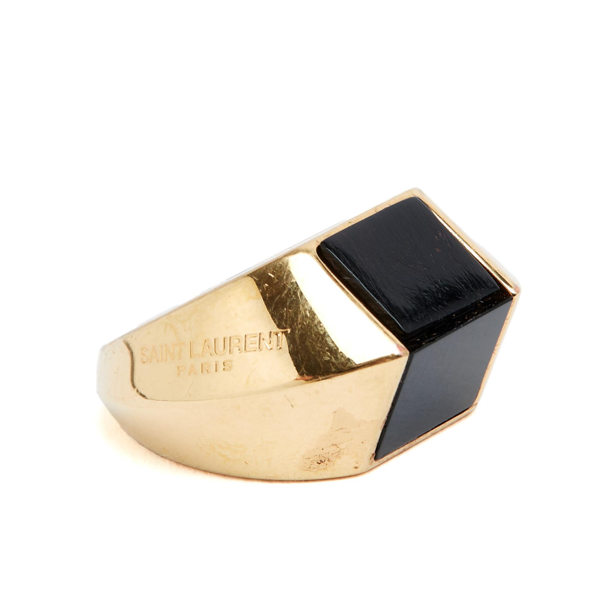 Bague Saint Laurent Opyum en métal doré et onyx de jais ou noir. Taille 7 (US) ou circonférence du doigt 54/55 mm, avec un diamètre interne de 17,35 mm. La bague a été portée mais reste en très bon état, parfaite pour une chevalière moderne.