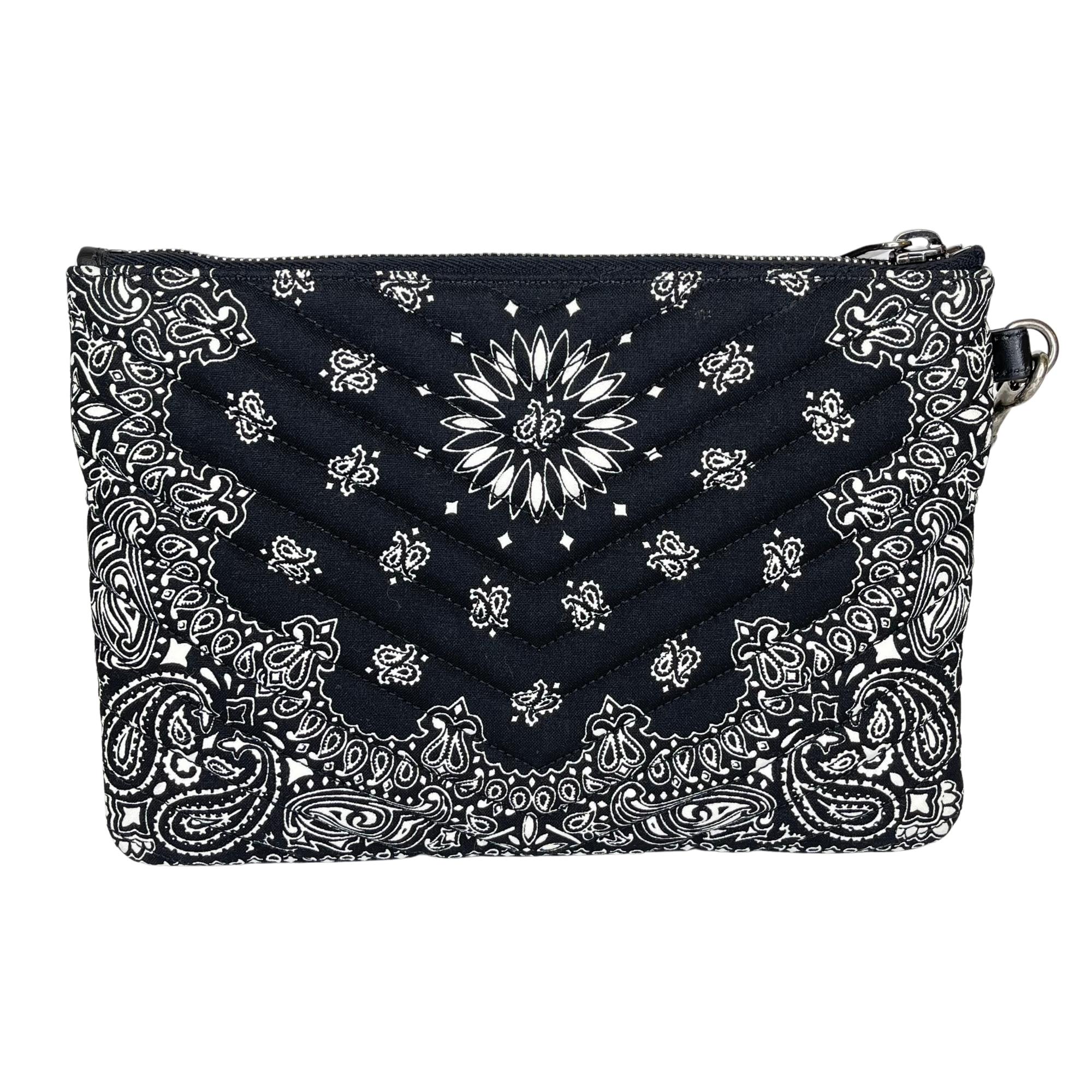 This pouch bag is made with black fabric with a paisley bandana print in white. The pouch features a polished aged silver YSL monogram logo at the front, an attachable black leather wristlet strap, top zip closure and an interior with black fabric