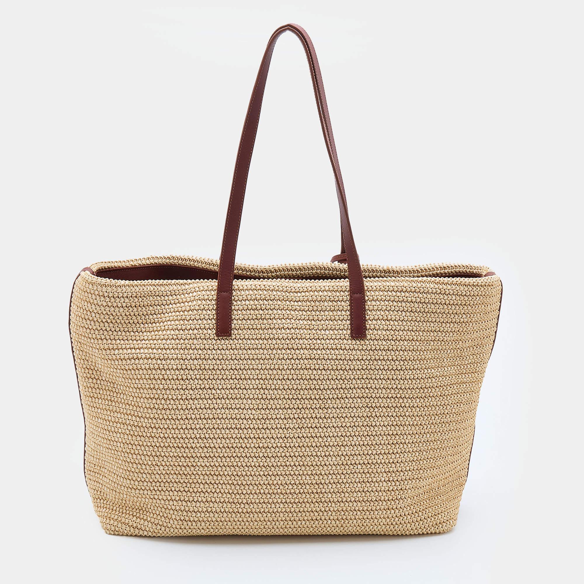 This Saint Laurent tote in beige woven raffia and brown leather may be perfect for vacations and beach dates, but it holds the power to effortlessly elevate chic tailoring too. It has a spacious size, with two shoulder handles and a tassel
