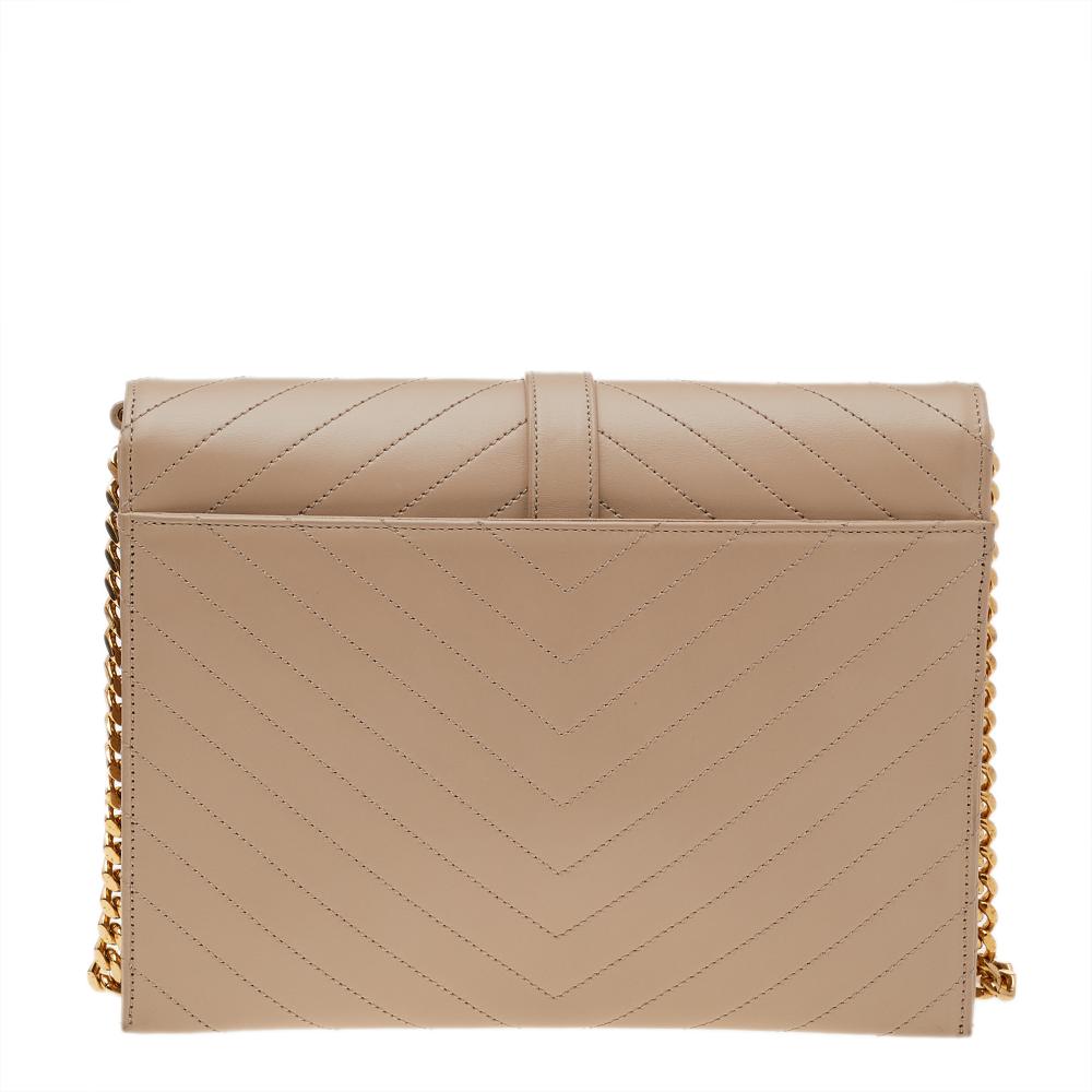 Fashioned using beige chevron-quilted leather into a structured silhouette, this Saint Laurent Monogram Envelope shoulder bag has high style and a timeless charm. It has a flap design and the front is highlighted with a gold-tone YSL logo. The
