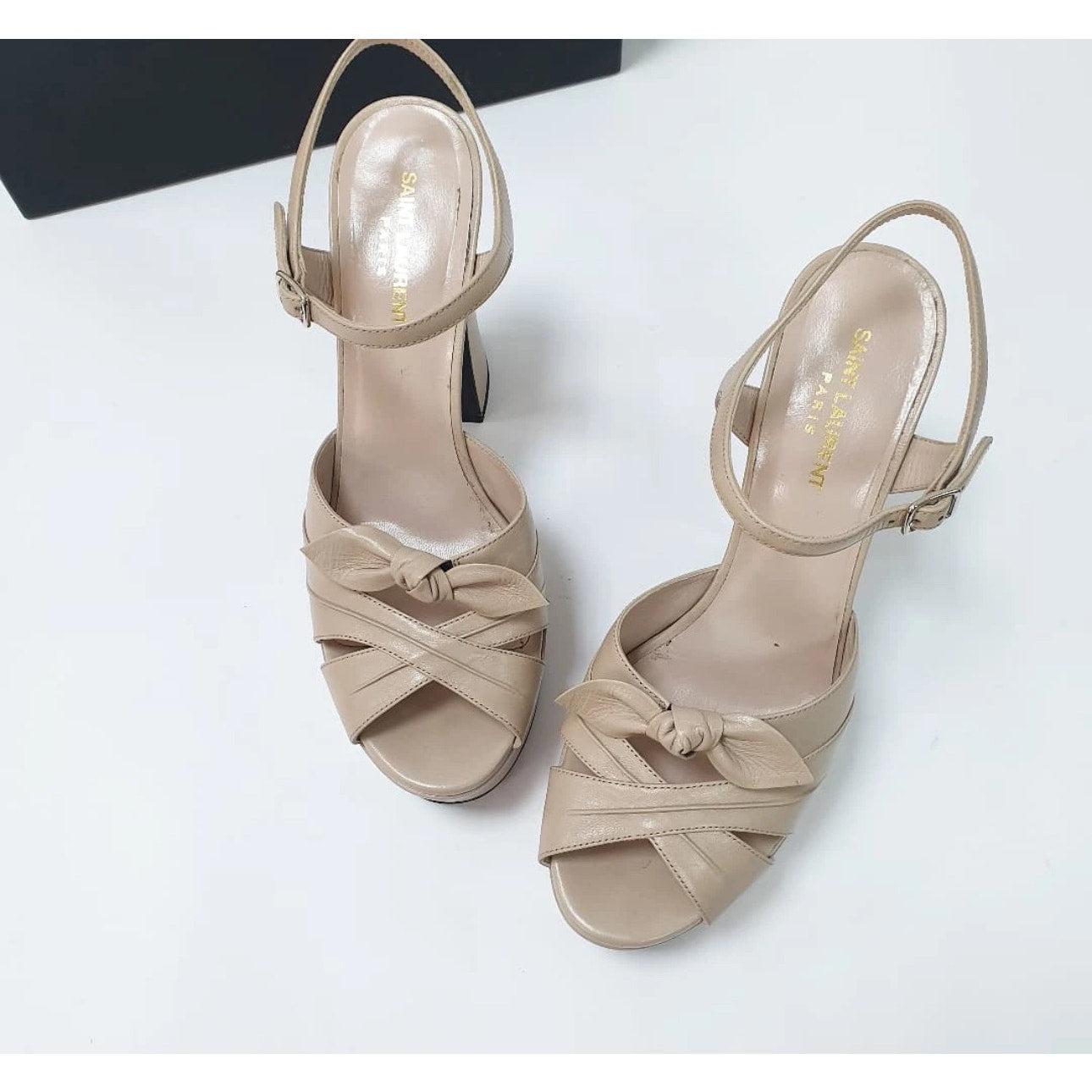 Erhöhen Sie Ihren Stil mit diesen atemberaubend schönen Saint Laurent Candy Bow Plateau Sandalen! Diese Sandalen aus luxuriösem beigem Leder sind ein echter Hingucker. 

Die mit Cut-Outs versehenen Kreuzriemen und die charmanten Schleifen auf dem