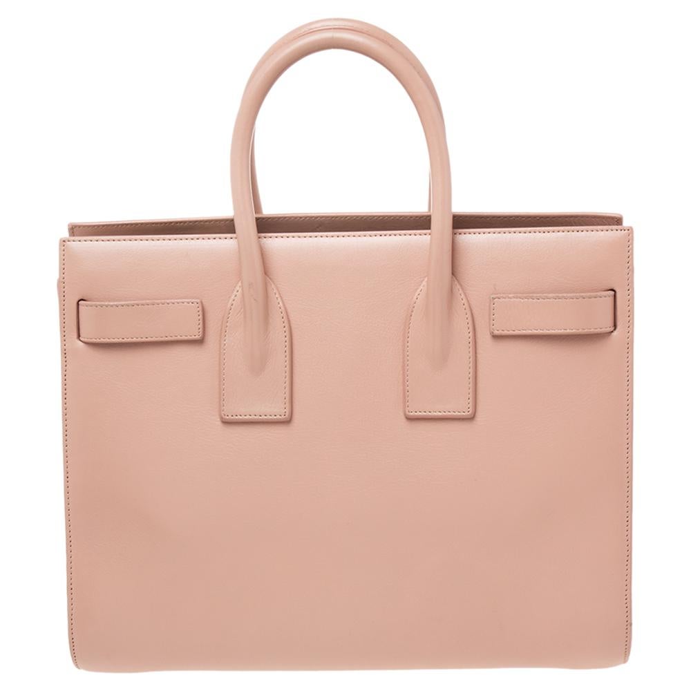 This Sac de Jour tote by Saint Laurent has a structure that truly spells sophistication. Crafted from beige leather, the bag is held by dual handles. It comes with a suede and fabric-lined interior with enough space to store your necessities, while