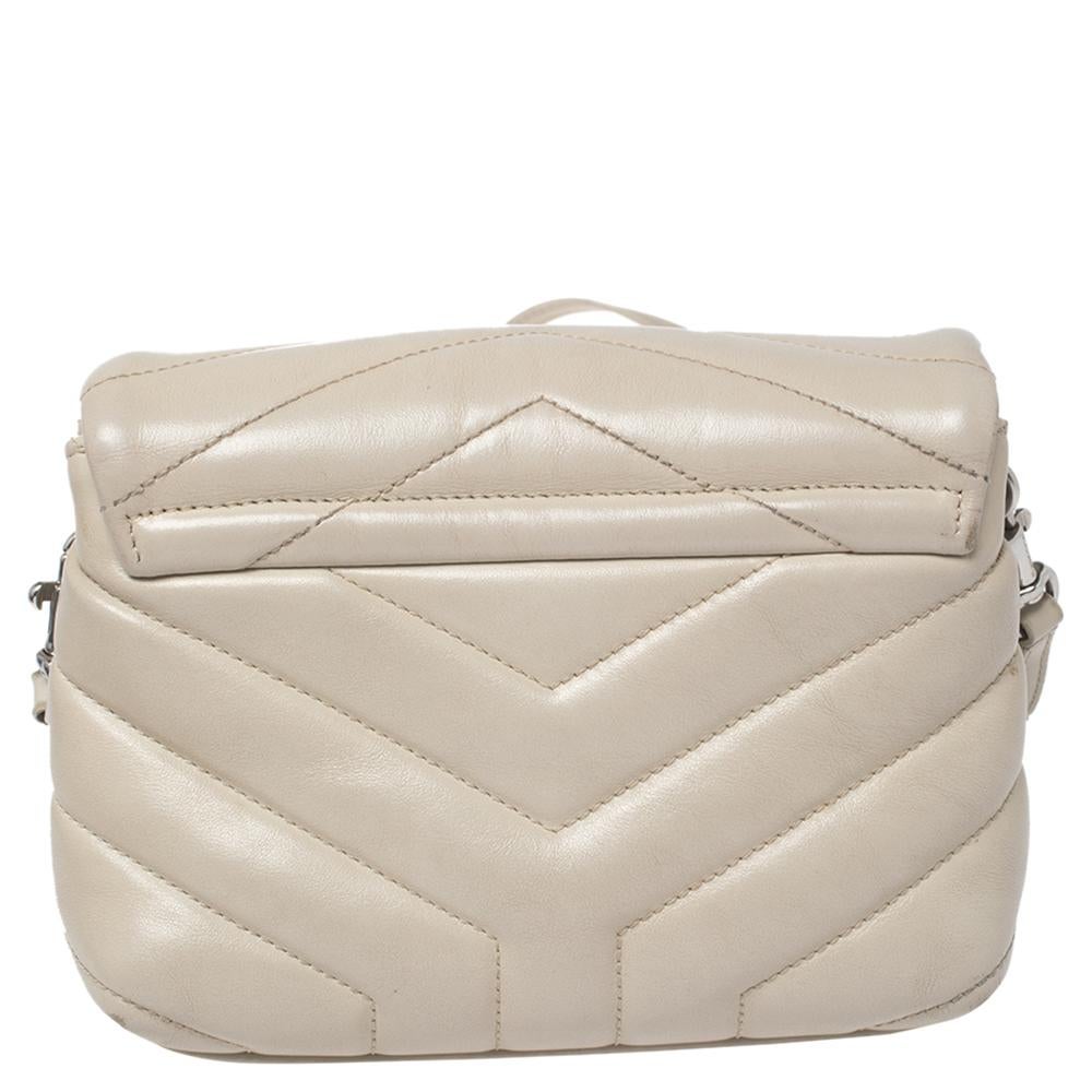 Diese exquisite Tasche von Saint Laurent ist ein schickes Accessoire, das die reiche Ästhetik und das elegante Design der Marke repräsentiert. Diese leicht zu tragende Tasche aus beigem Matelassé-Leder hat einen Überschlag mit dem silberfarbenen