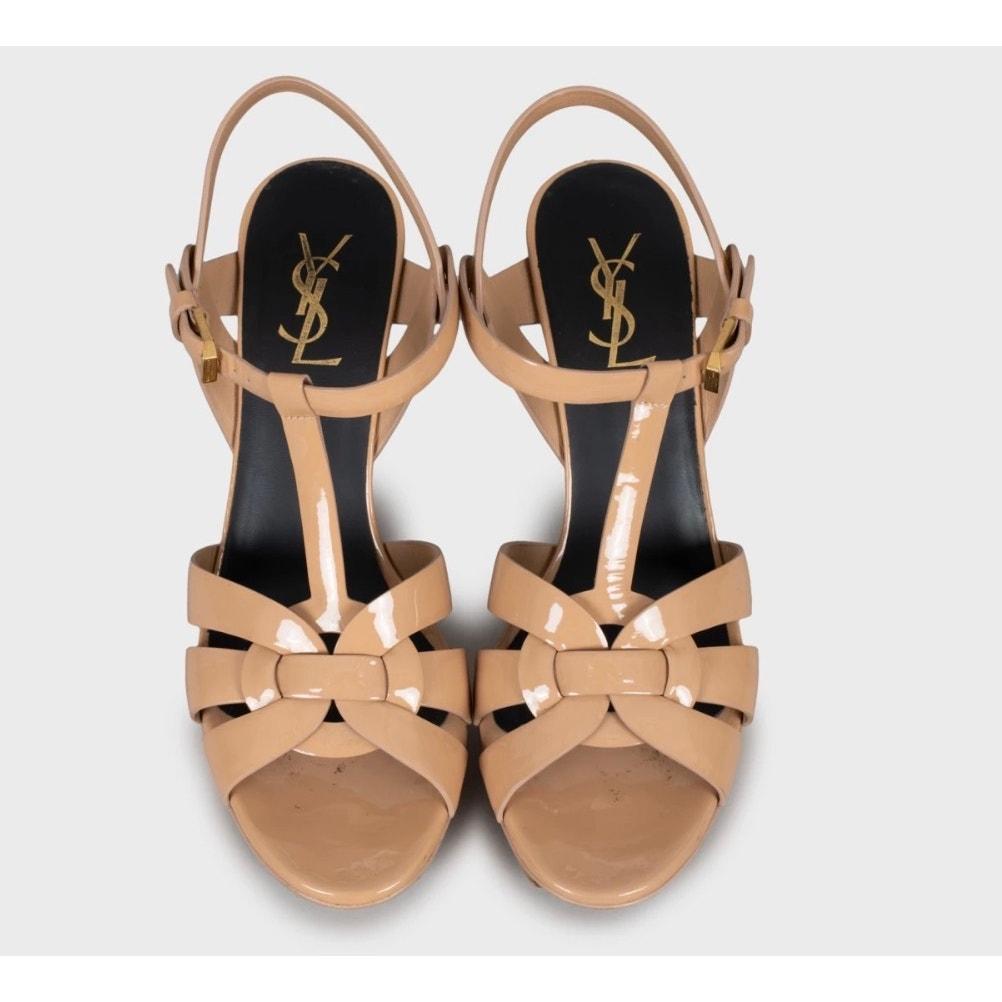 Esci con stile con questi sandali con zeppa in pelle beige di Saint Laurent! Questi sandali presentano un cinturino regolabile alla caviglia per una vestibilità sicura e confortevole, un elegante tacco a zeppa e un design aperto in punta, perfetto