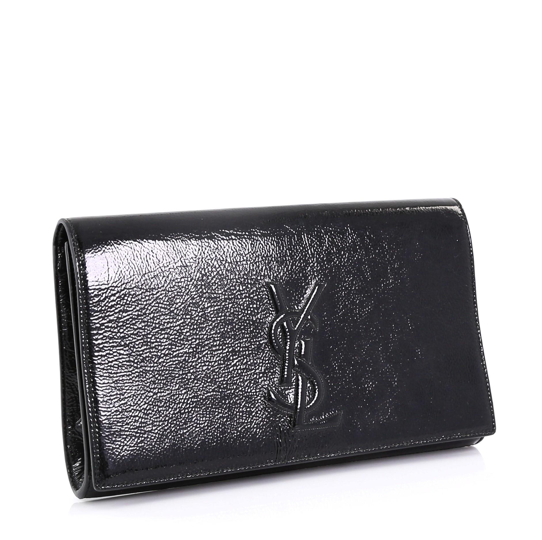 This Saint Laurent Belle de Jour Clutch Leather Small, crafted in black crinkled patent leather, features an embossed YSL monogram logo and gold-tone hardware. Its magnetic snap closure opens to a black satin interior with slip pocket. 

Estimated