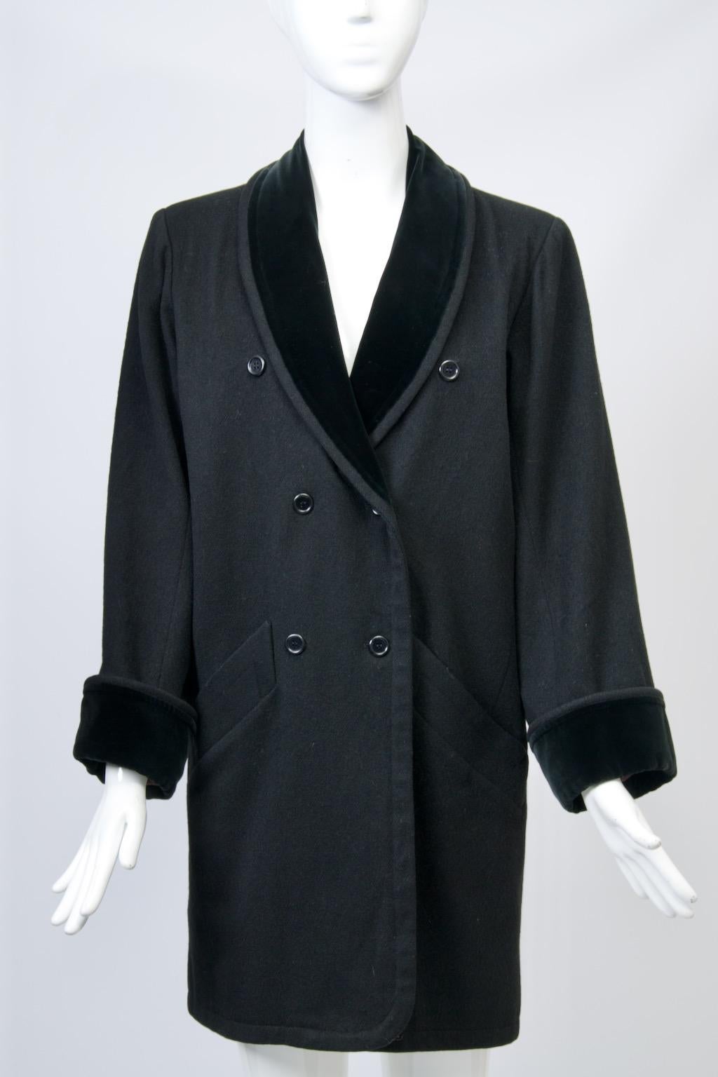 c.anni '80 Yves Saint Laurent cappotto in lana nero a 3/4 con finiture in velluto eseguito nello stile smoking per cui era famoso. Questa versione è a doppio petto e presenta un collo a scialle e polsini risvoltati in velluto nero. Il top spazioso e