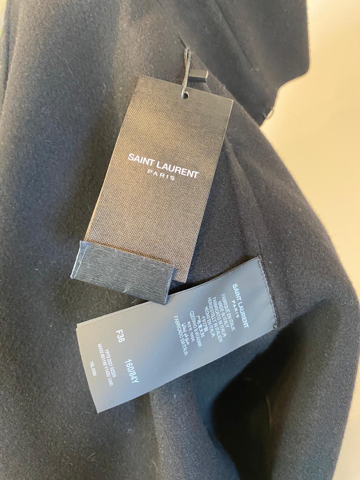 Mantella in cashmere nero di Saint Laurent con bordo in pelle. In cashmere con bottoni dorati con logo e catena per chiudere i lati della mantella. 
FW 20/21
Nuovo con tag. 
107 cm di lunghezza
Spalle 44 cm
Manicotto cm
Taglia FR 36