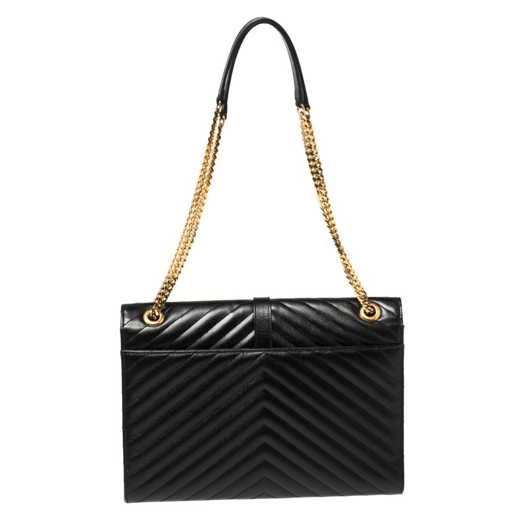 Elevate your outfits with this black-hued Monogram Envelope bag by Saint Laurent. It is crafted in Matelasse leather and features the YSL logo in gold-tone metal on the front flap. The stunning creation has a zip pocket on the interior and is held