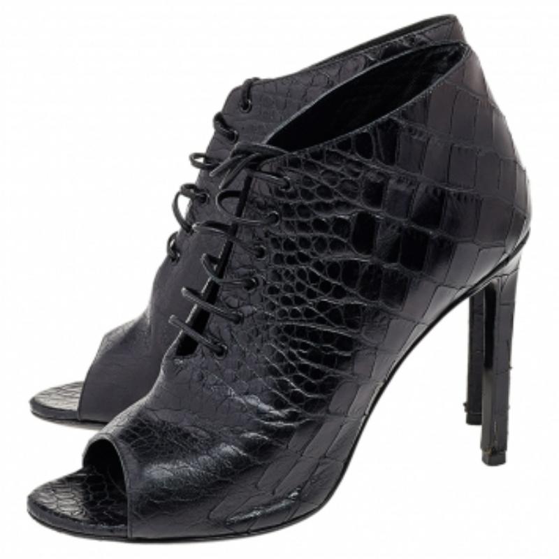 Añade un acabado a la moda con este par de botines de Saint Laurent. Confeccionados en piel, los botines llevan un exterior con relieve de cocodrilo y se combinan con cordones. Peep toes, plantillas forradas y unos tacones de 19 cm las completan.