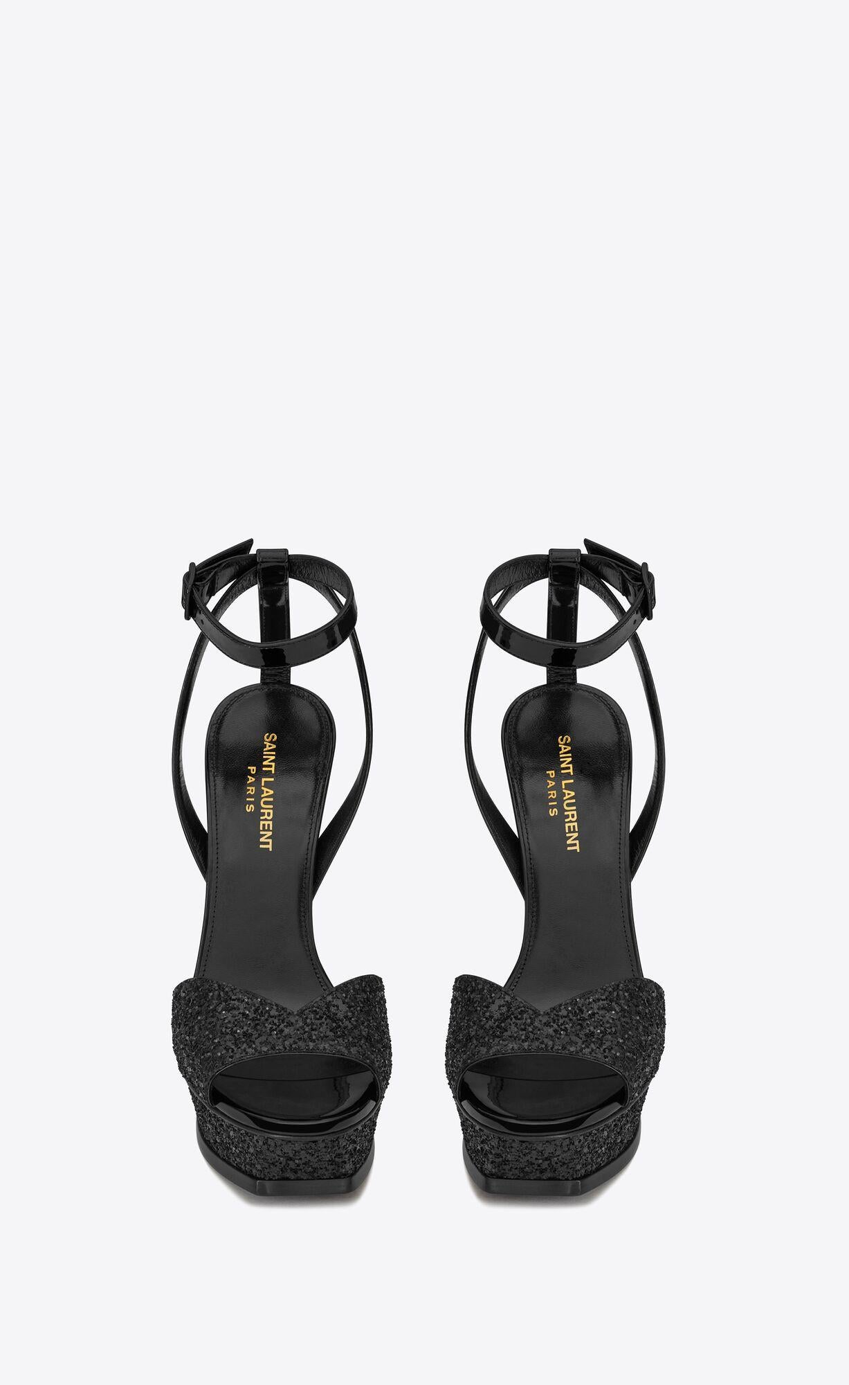 Saint Laurent Black Glitter and Patent Leather Tribute Lips Sandal 

These Saint Laurent Tribute Lips sandals feature glitter, a v-cut vamp, beveled platform, a stiletto heel, open toe, leather sole, and adjustable ankle strap. Brand new.

Size: 41