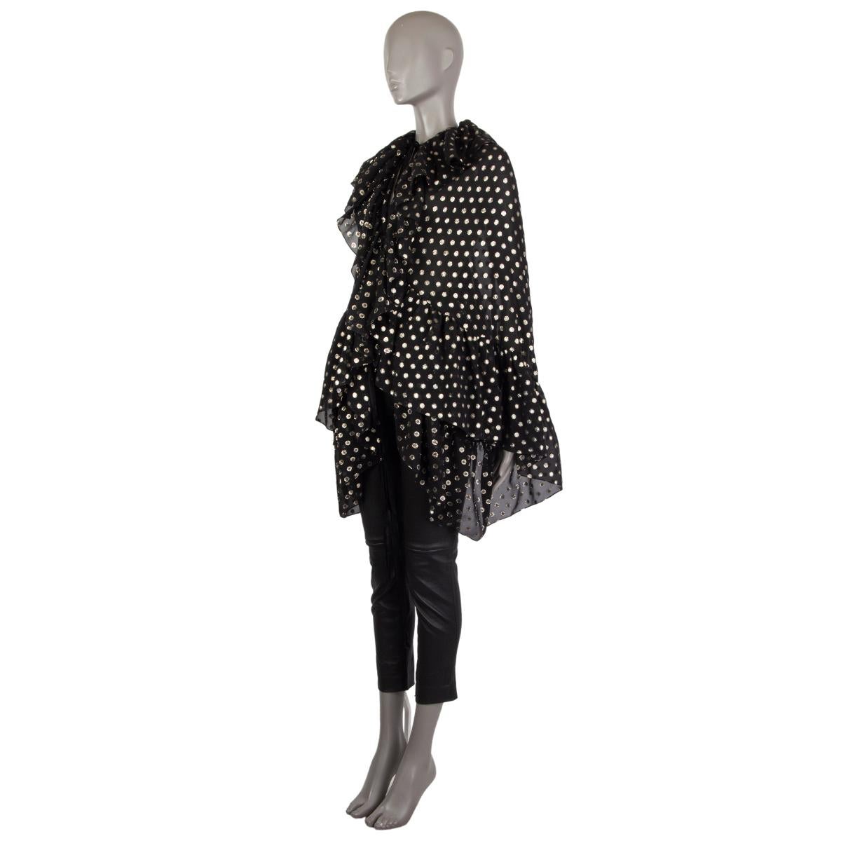 Saint Laurent gepunktetes Chiffon-Cape aus schwarzer und goldener Seide (83%) und Metall (7%). Mit Rüschenbesatz und gerafftem Dehnbund. Wird im Nacken und in der Taille mit Riemen gebunden. Wurde getragen und ist in ausgezeichnetem Zustand. 

Tag