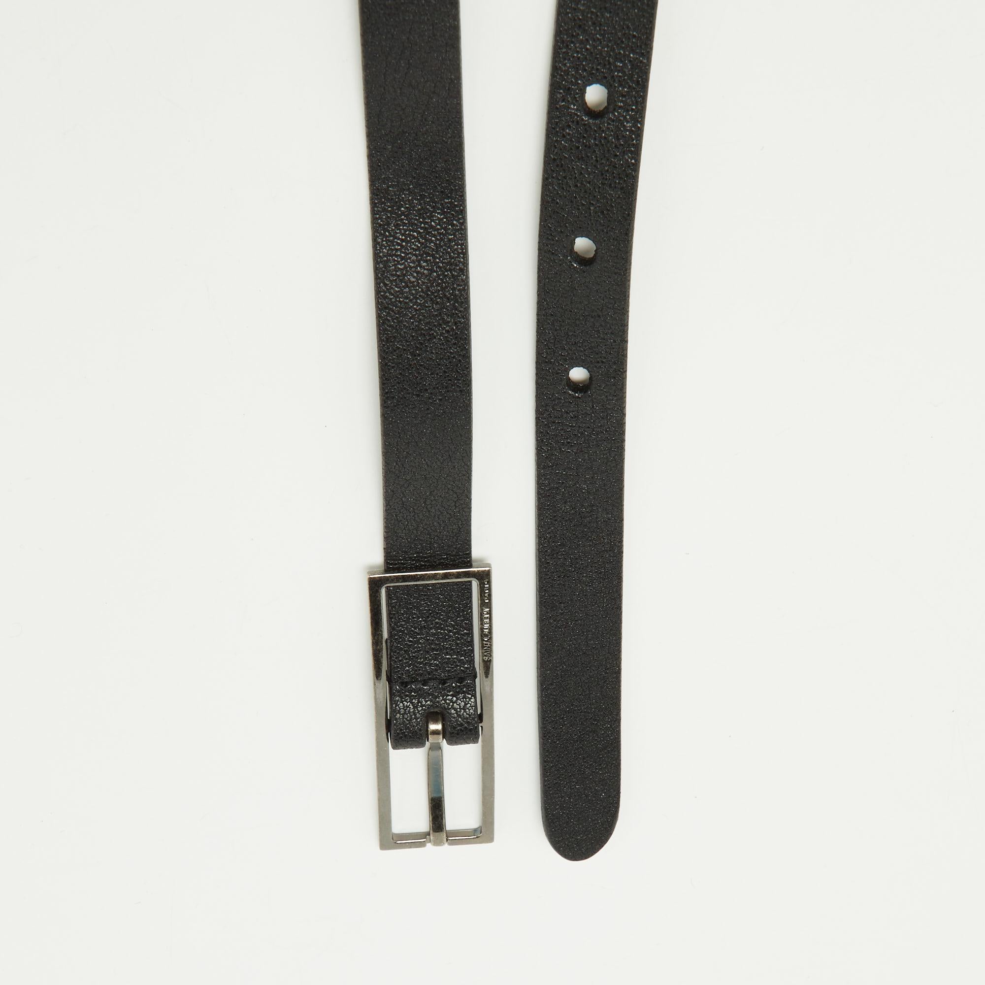 This slim belt from Saint Laurent redefines simplistic fashion. The belt's appeal lies in its minimalistic style with only the texture of the black leather and the gunmetal-tone buckle adding to its show. It is 95 cm long with the brand's name