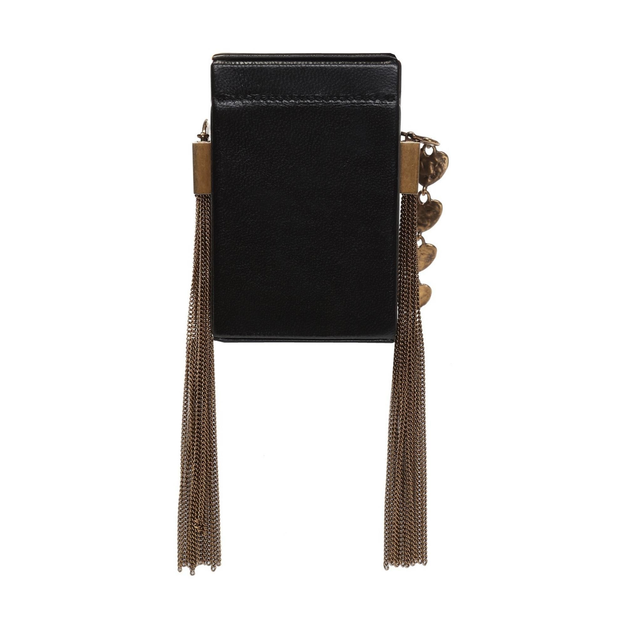 Black cigarette case from Saint Laurent. Made of leather. Gold-tone logo embossed on the front. Decorative fringes on the side. Chain shoulder strap featuring a heart motif. Antiqued gold-tone metal hardware.

COLOR: Black with aged gold tone