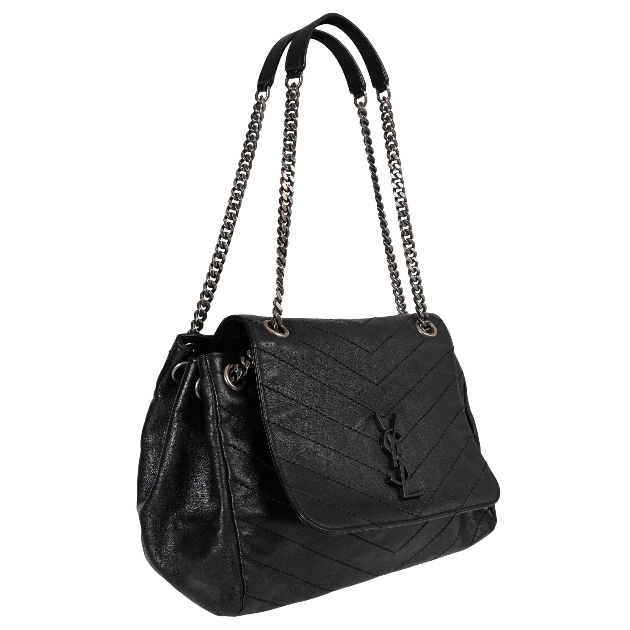 This 100% authentic Saint Laurent Nolita Medium shoulder bag in black chevron-quilted vintage leather embodies effortless sophistication. Featuring an antique silver-tone curb chain strap and a magnetic flap closure adorned with a leather-covered