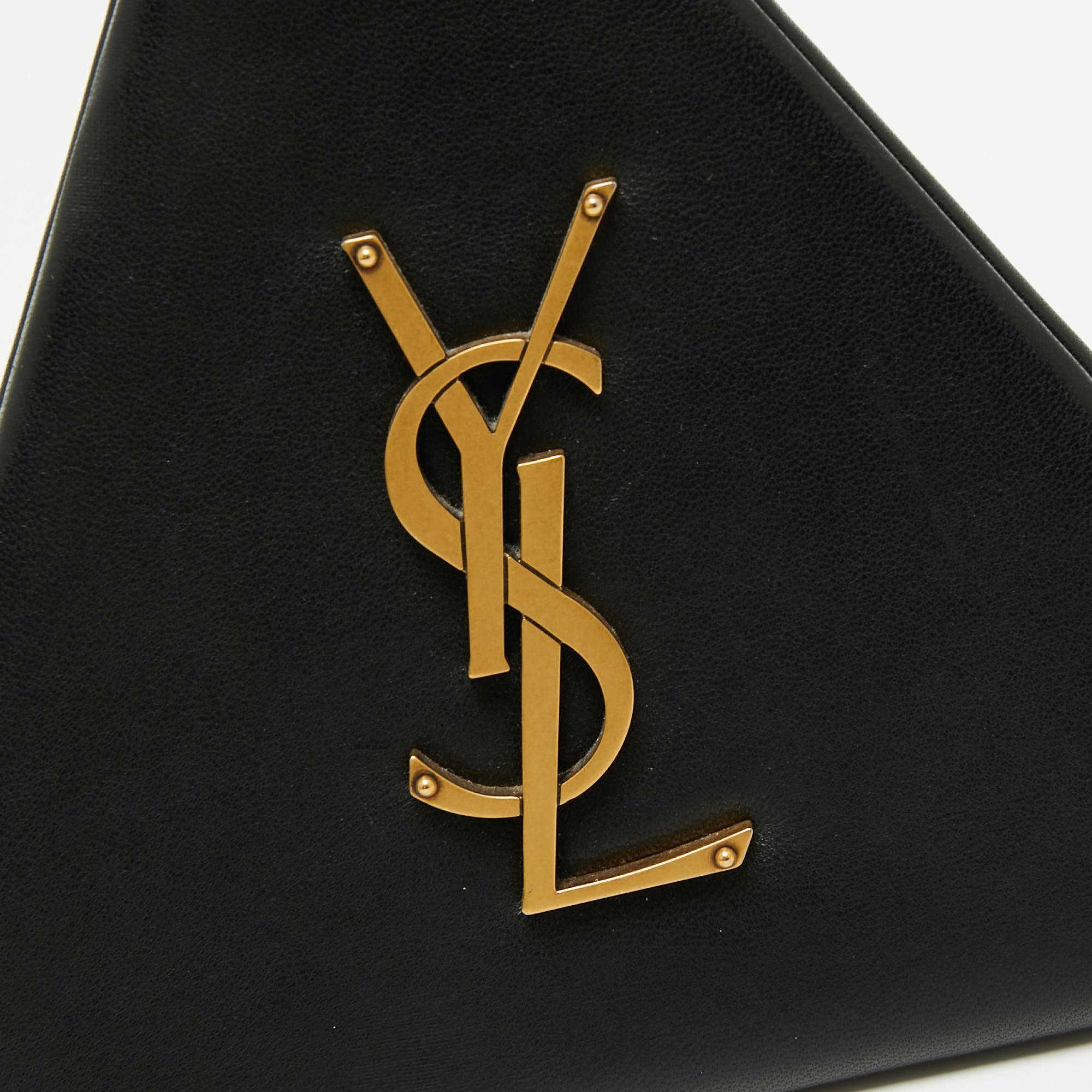 This beautiful wristlet clutch from Saint Laurent is just the right party piece! It is made from black leather and has an amazing pyramid box shape that adds to its striking appeal. It is complete with a gold-tone YSL logo on the front and has a
