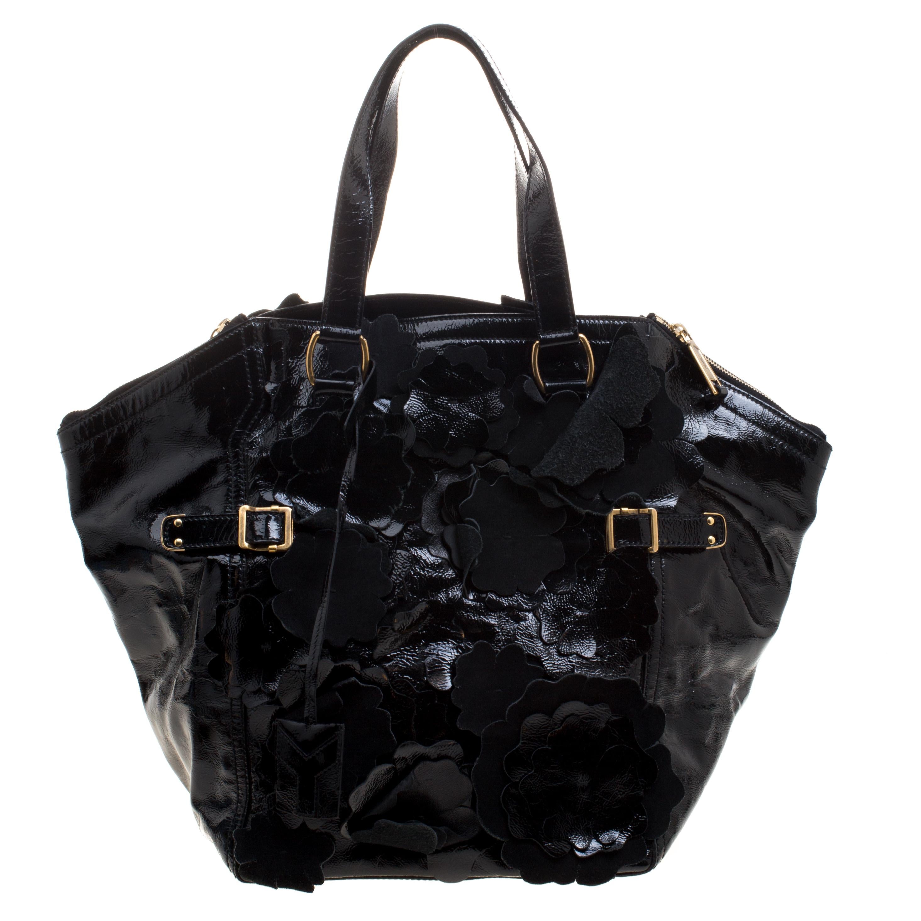 Featuring a unique shape, this Saint Laurent Downtown tote is crafted in a black patent leather with floral applique on it that lends it a gorgeous feminine touch. It features a top zipper closure, gold-tone accents and fitted with two flat straps