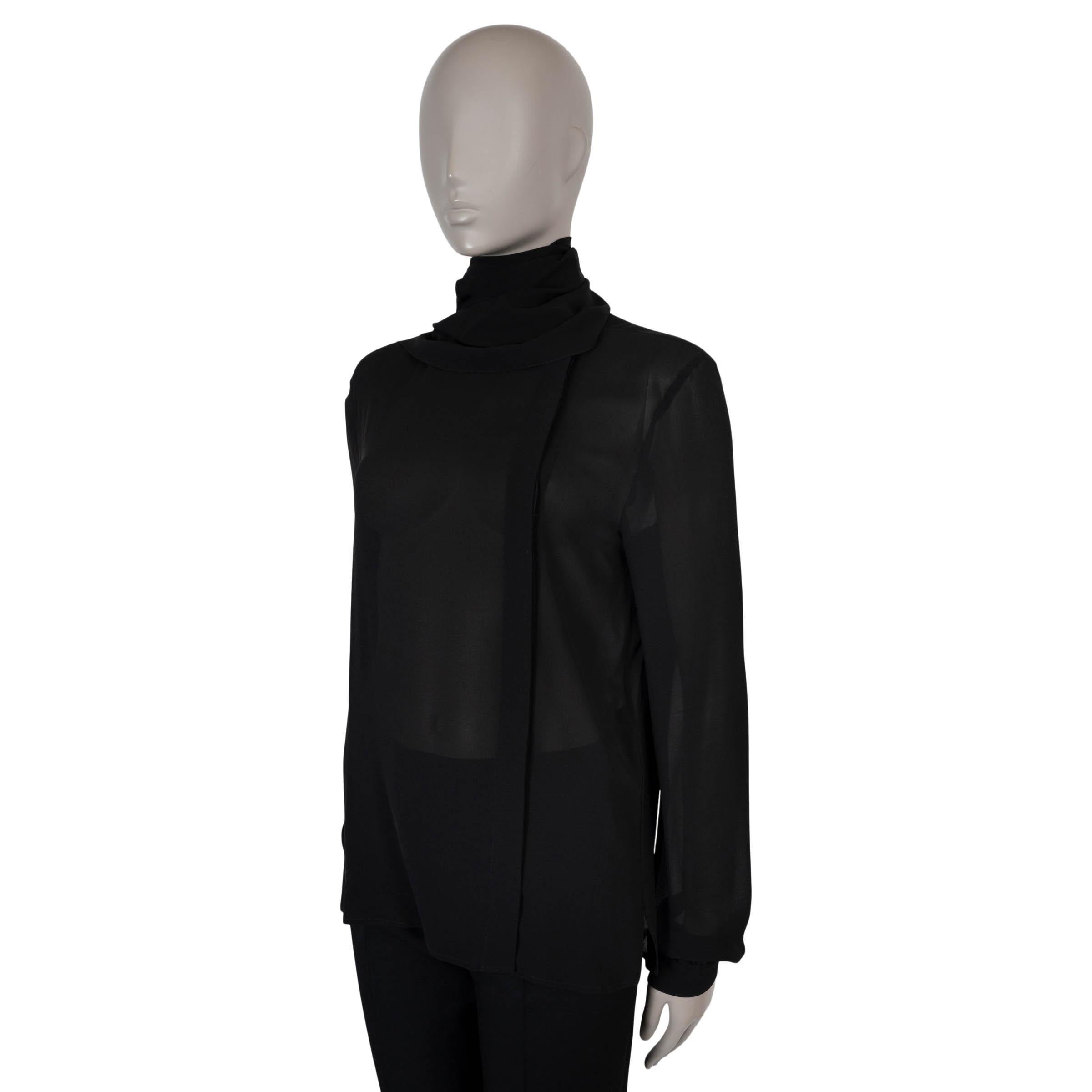 Esta blusa 100% auténtica Saint Laurent está confeccionada en seda negra semitransparente (100%). Presenta una silueta fluida y relajada con un refinado escote redondo y un pañuelo de seda adjunto que envuelve elegantemente el cuello. Diseñado con