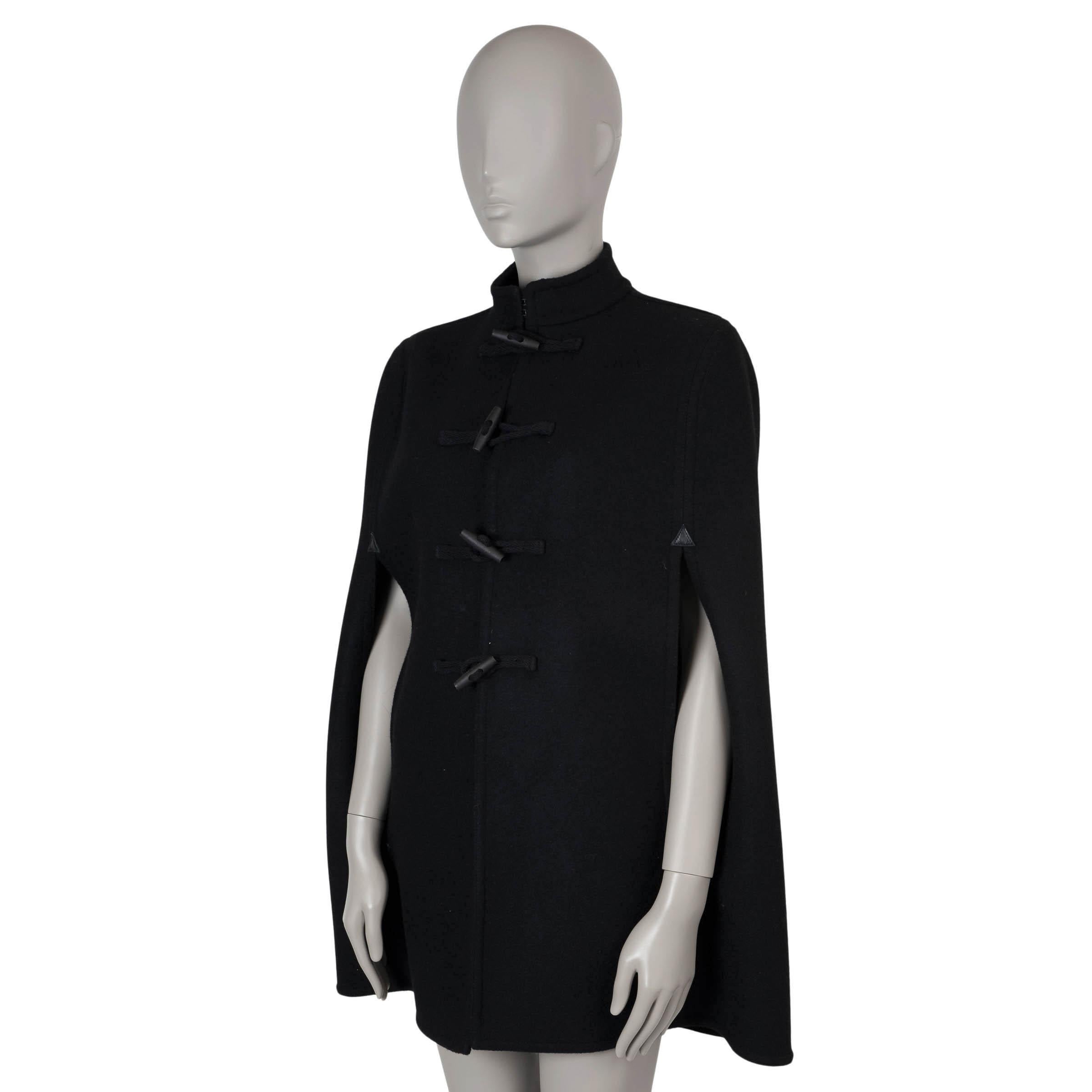 Questa mantella in lana nera (100%) autentica Saint Laurent emana un'eleganza senza tempo. Presenta un elegante scollo a goccia e toppe in pelle all'apertura delle braccia per aggiungere dettagli. Il mantello si chiude con alamari e corde incise con