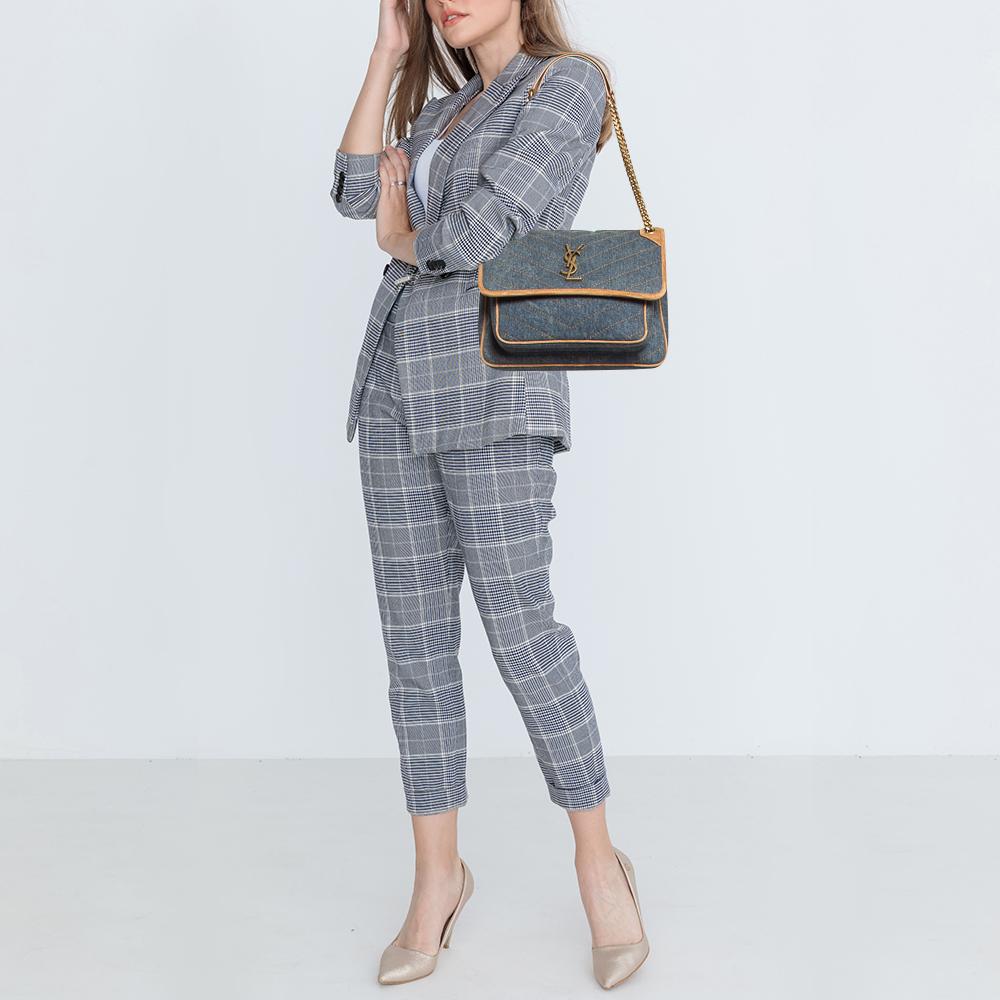 Carry this bag from Saint Laurent without compromising on style. This aged leather bag comes in a relaxed style with shoulder handles and a YSL-detailed flap closure. The Niki bag is equipped with a canvas and leather-lined interior sized to hold