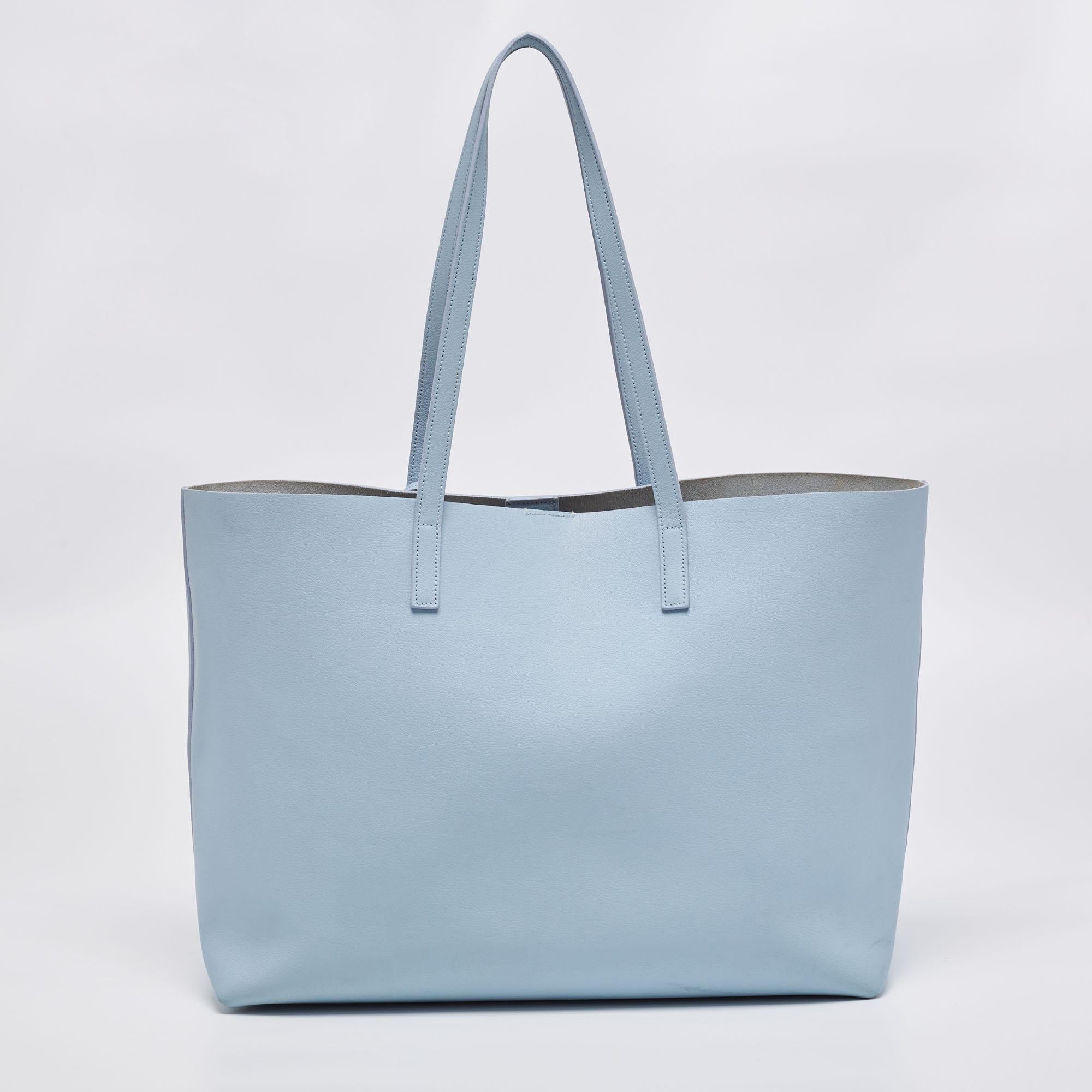 This Saint Laurent tote is all you need while running errands. Created from blue leather, it features a brand signature on the front, dual handles at the top, and gold-tone hardware. The suede-lined interior of the bag is spacious enough to make it