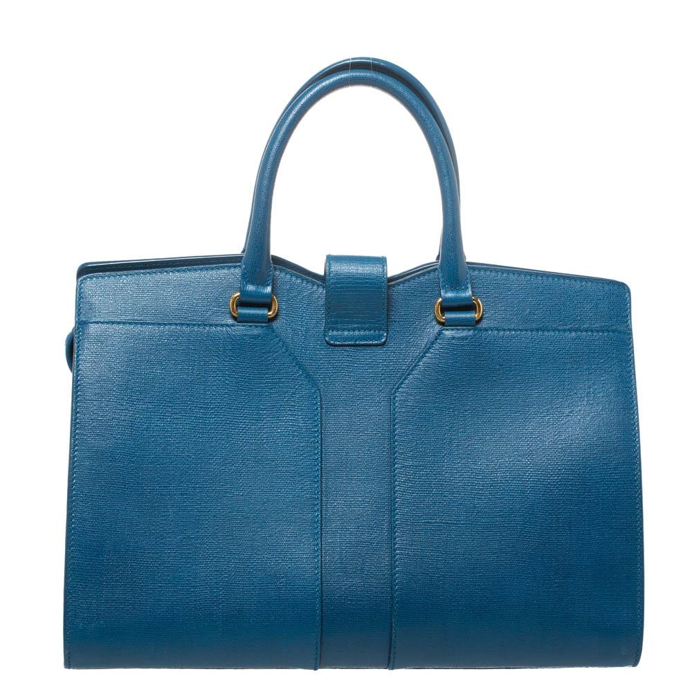 This elegant blue-hued Cabas Chyc tote from Saint Laurent is ideal for everyday use. Crafted from leather, the bag is detailed with a gold-tone hardware Y motif snap closure and dual-rolled handles. The top zip closure opens to a spacious interior