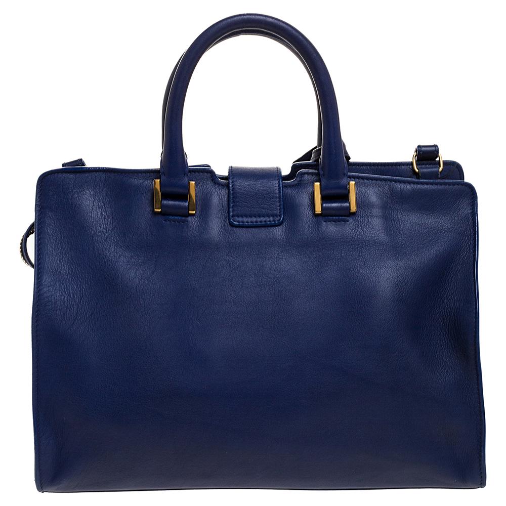 This elegant blue Cabas Ligne Y tote bag from Saint Laurent is ideal for everyday use. Crafted from leather, the bag is detailed with a gold-tone Y motif snap closure, dual handles, detachable shoulder strap and protective metal feet at the bottom.