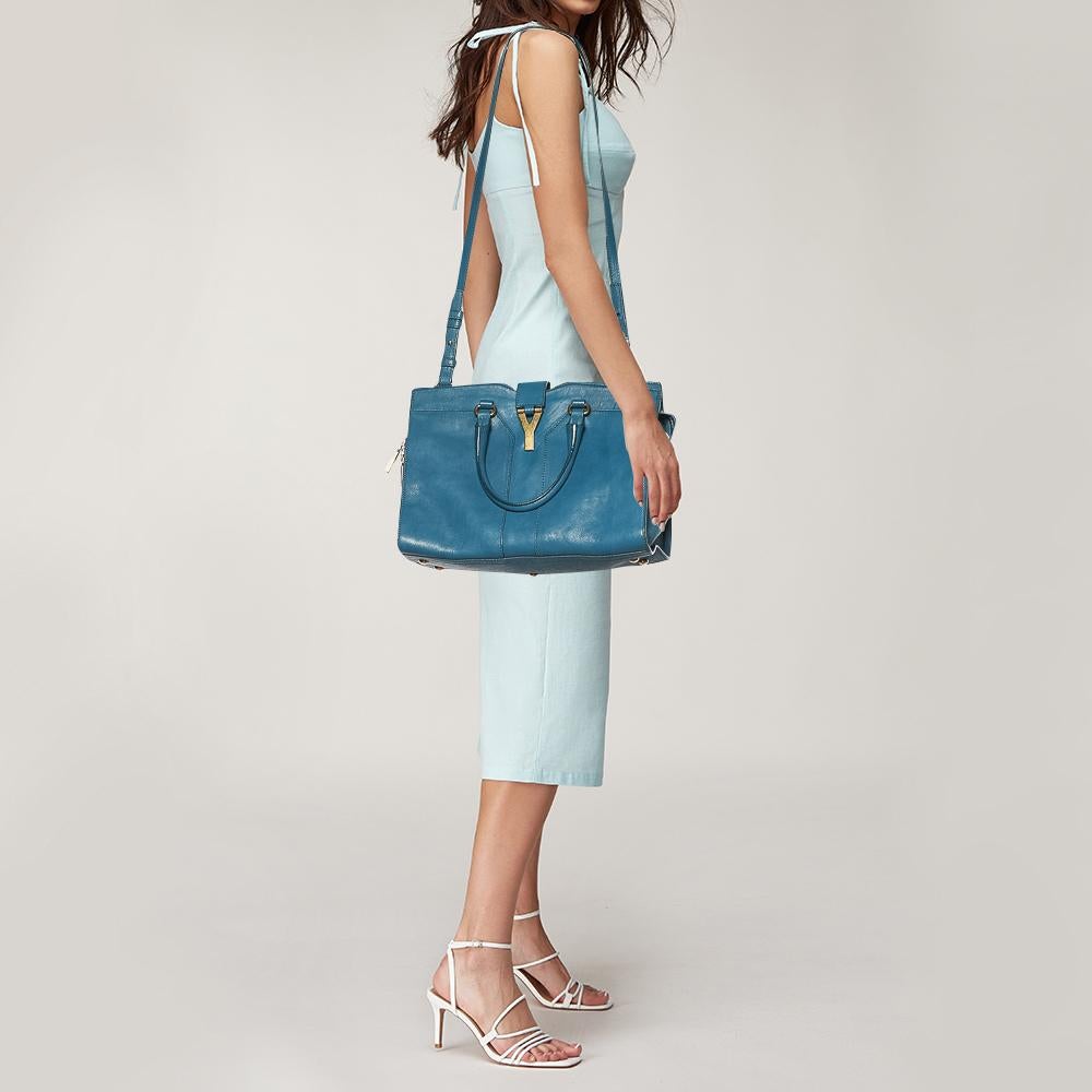 This elegant blue Cabas Chyc tote from Saint Laurent is ideal for everyday use. Crafted from leather, the bag is detailed with a gold-tone Y motif snap closure and dual-rolled handles. The top zip closure opens to a spacious interior that is