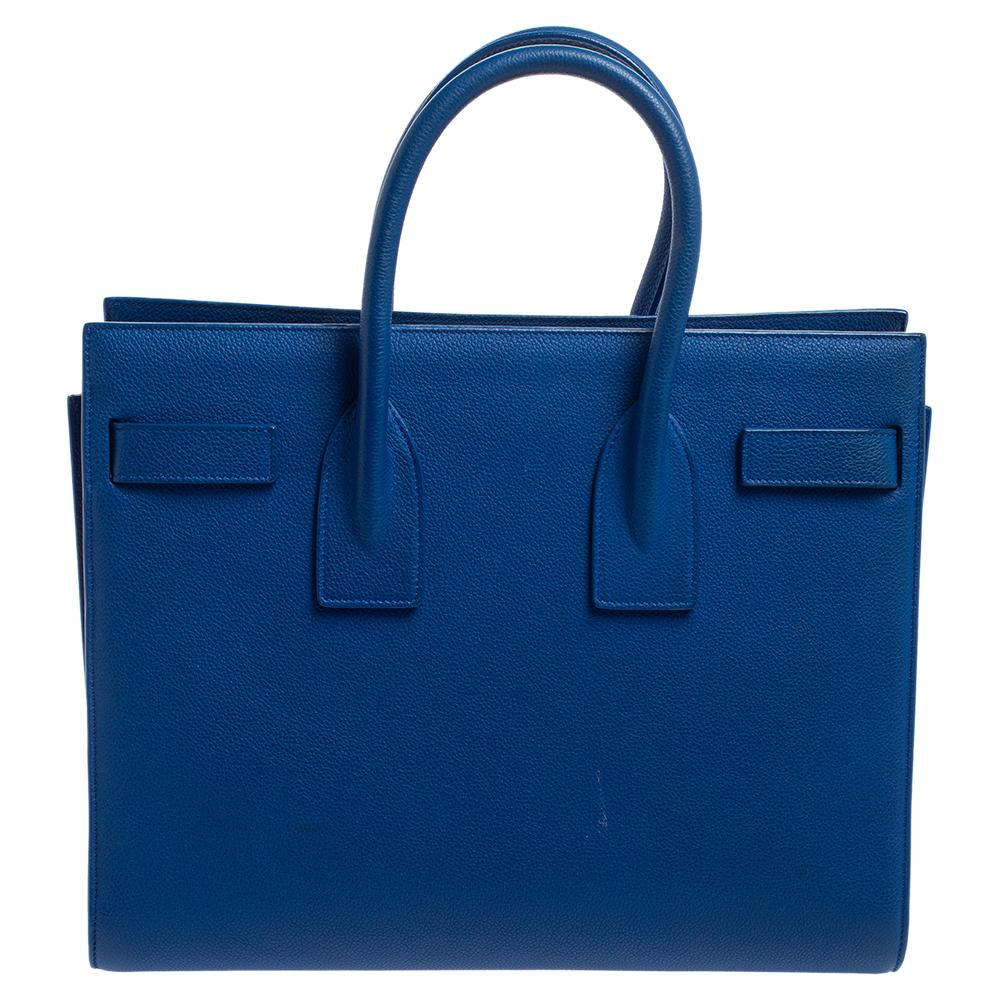 This Sac de Jour tote by Saint Laurent has a structure that simply spells sophistication. Crafted from blue leather, the bag is held by double top handles. The tote comes with a fabric-lined interior with enough space to store your necessities and