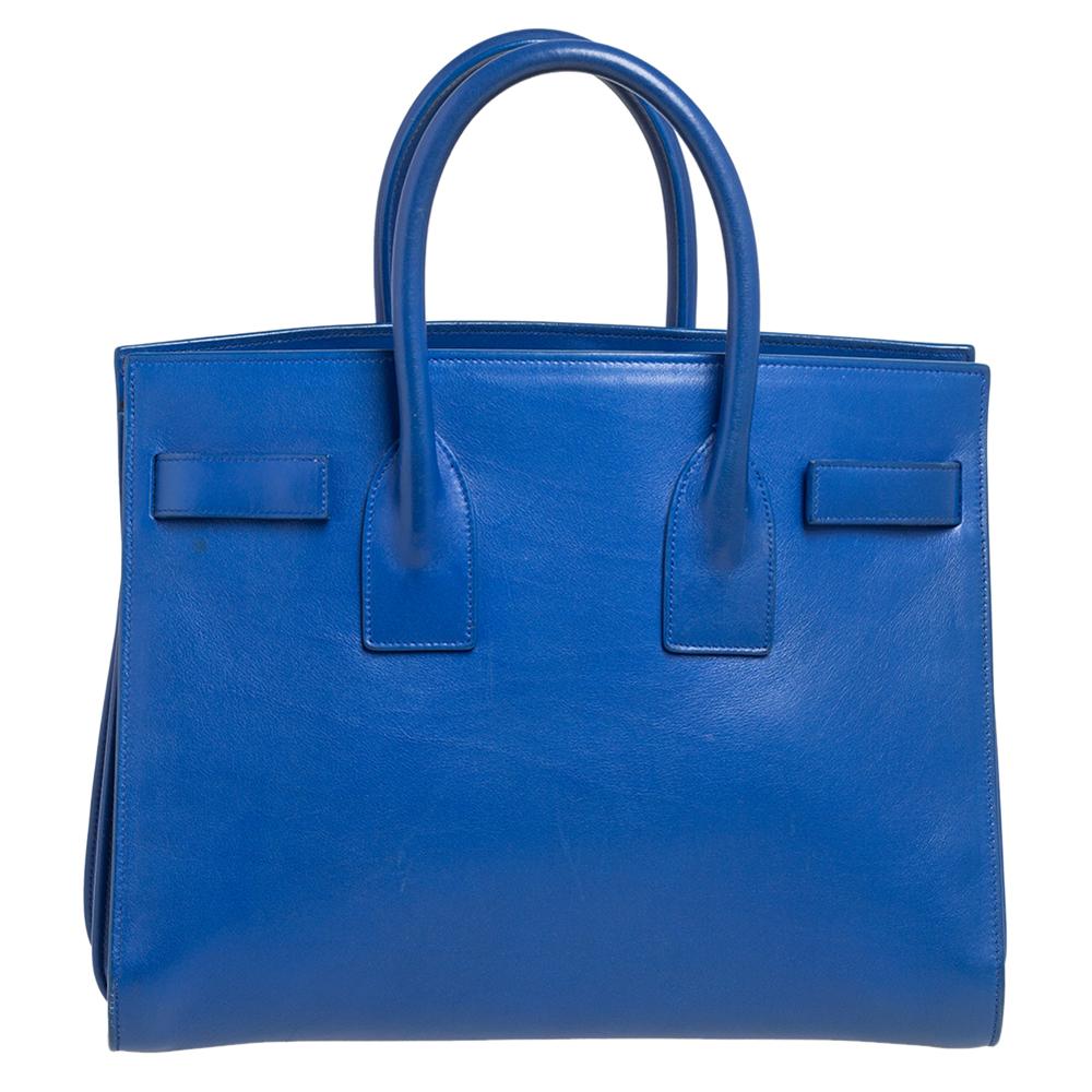 This Sac de Jour tote by Saint Laurent has a structure that simply spells sophistication. Crafted from blue leather, the bag is held by double top handles. The tote comes with a suede-lined interior with enough space to store your necessities and