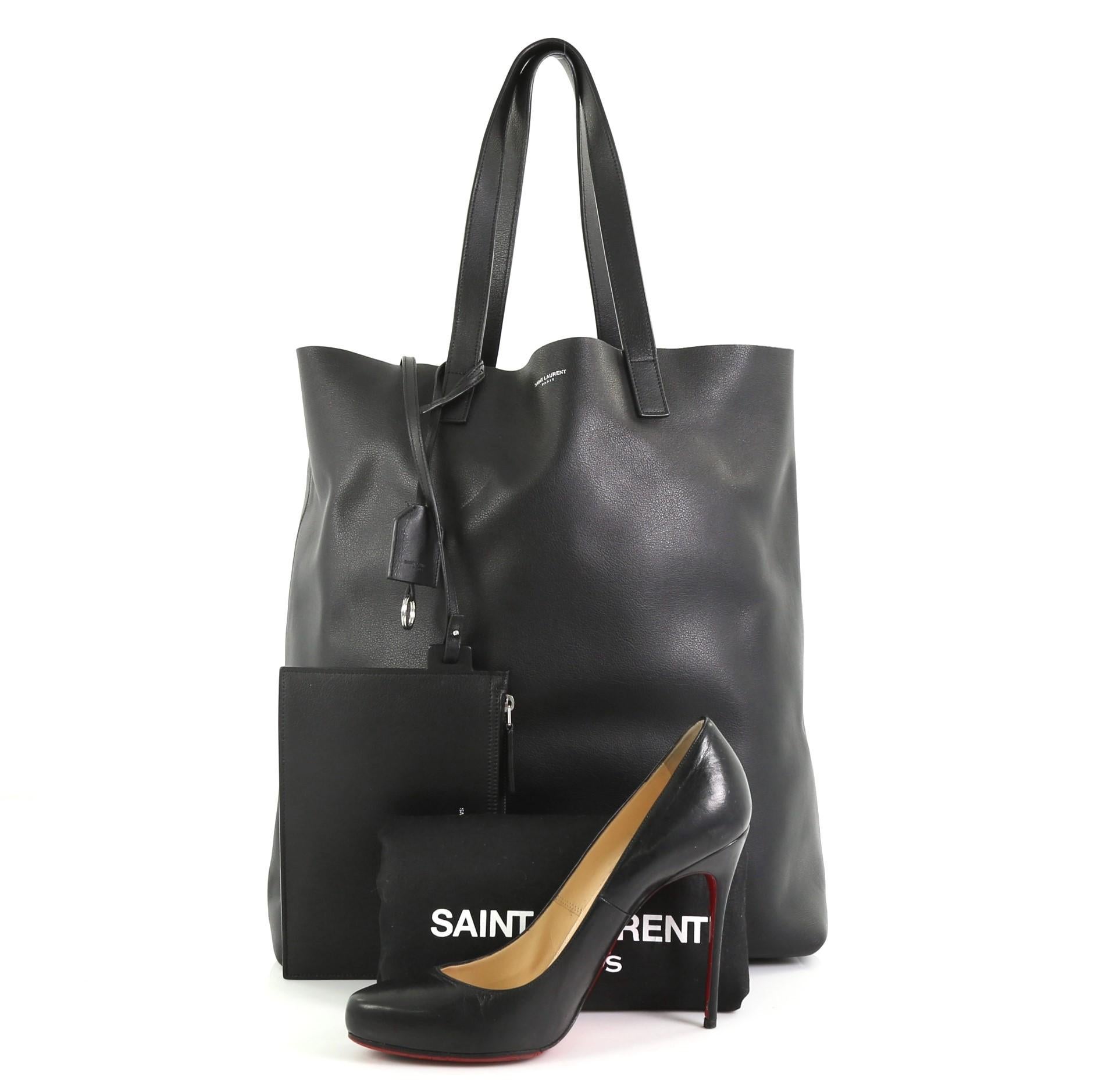 This Saint Laurent Bold Tote Leather Medium, crafted in black leather, features dual leather handles, stamped Saint Laurent logo, and silver-tone hardware. It opens to a black raw leather interior. **Note: Shoe photographed is used as a sizing