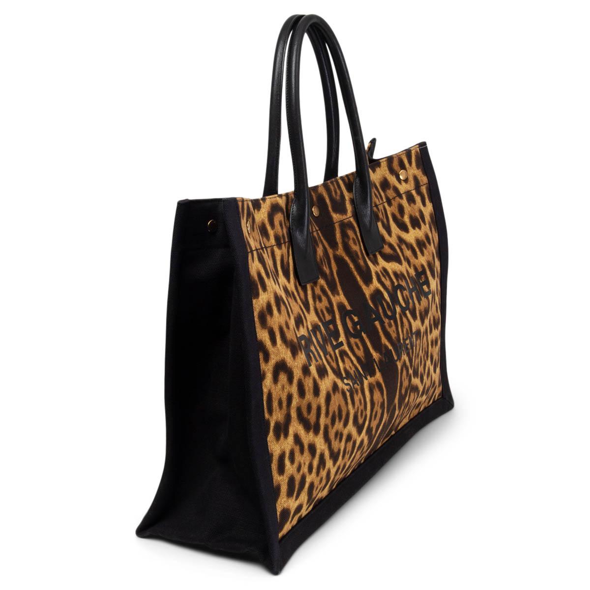 100% authentic Saint Laurent Canvas Leopard Print Rive Gauche Tote in brown, beige and black canvas with calfskin handles. Opens with a push button and is lined i black canvas with one big zipper pocket against the back. Has been carried and is in