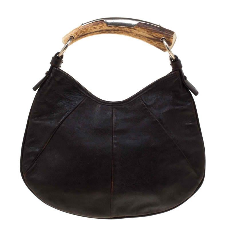 You will love to have this Saint Laurent Paris Mombasa hobo. Crafted from brown leather and held by a metal horn-shaped handle, it is a beauty. Fastened by a snap magnetic button, the interior is lined with suede to house your essentials with