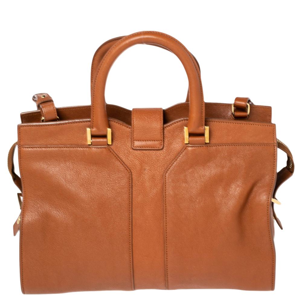 This elegant brown-hued Cabas Chyc tote from Saint Laurent is ideal for everyday use. Crafted from leather, the bag is detailed with a gold-tone Y motif snap closure, dual-rolled handles, and a shoulder strap. The top zip closure opens to a spacious