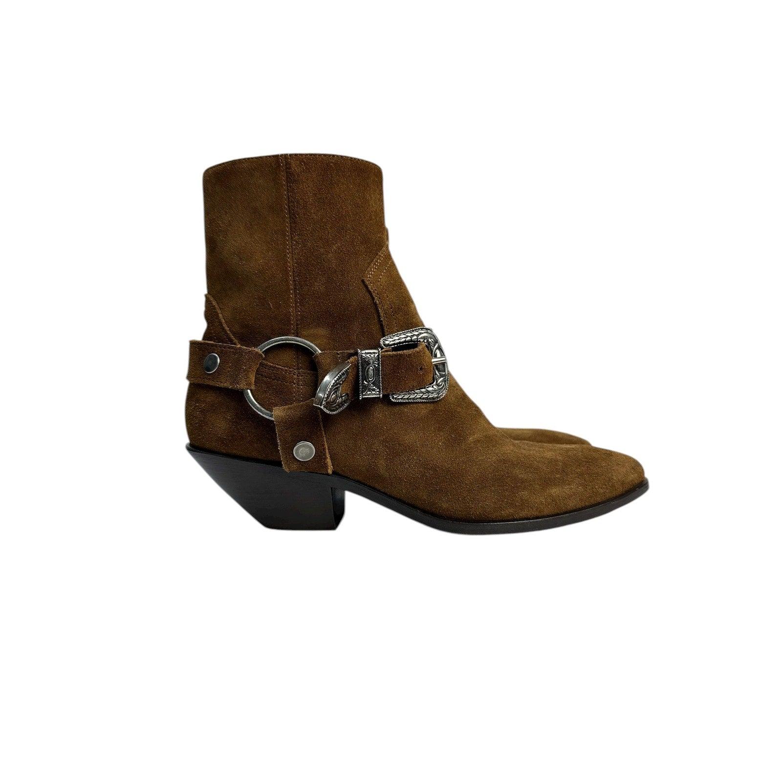 Estas botas de estilo occidental de Saint Laurent están confeccionadas en ante marrón intenso e incorporan hebillas y anillas laterales grabadas en tono plateado. El tacón estructurado y la punta puntiaguda aportan un toque atrevido a cualquier