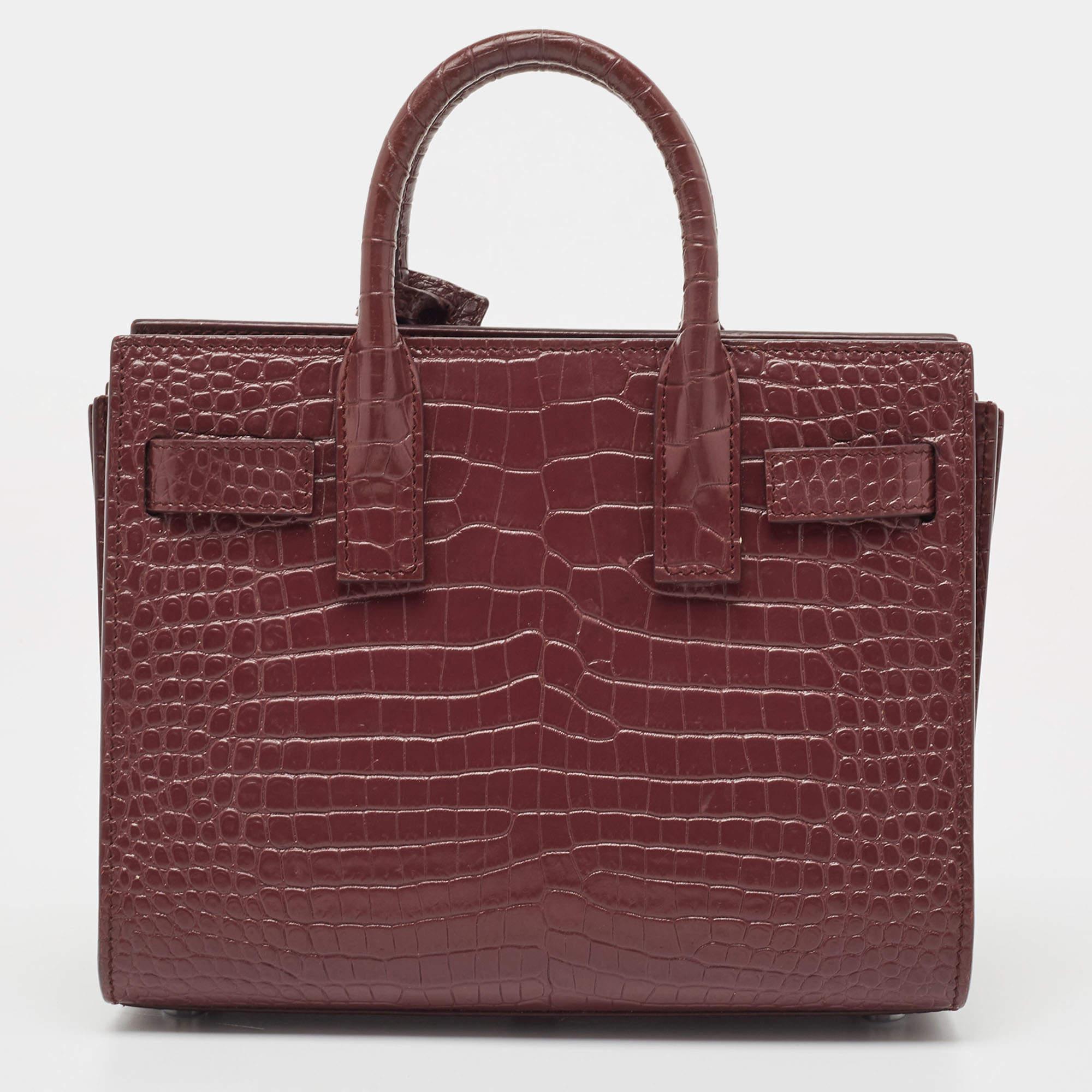 This Sac de Jour tote by Saint Laurent has a structure that exhibits a sophisticated image. Crafted from croc-embossed leather, the bag can be carried in a chic way by double top handles and a shoulder strap. The tote comes with a stylish interior