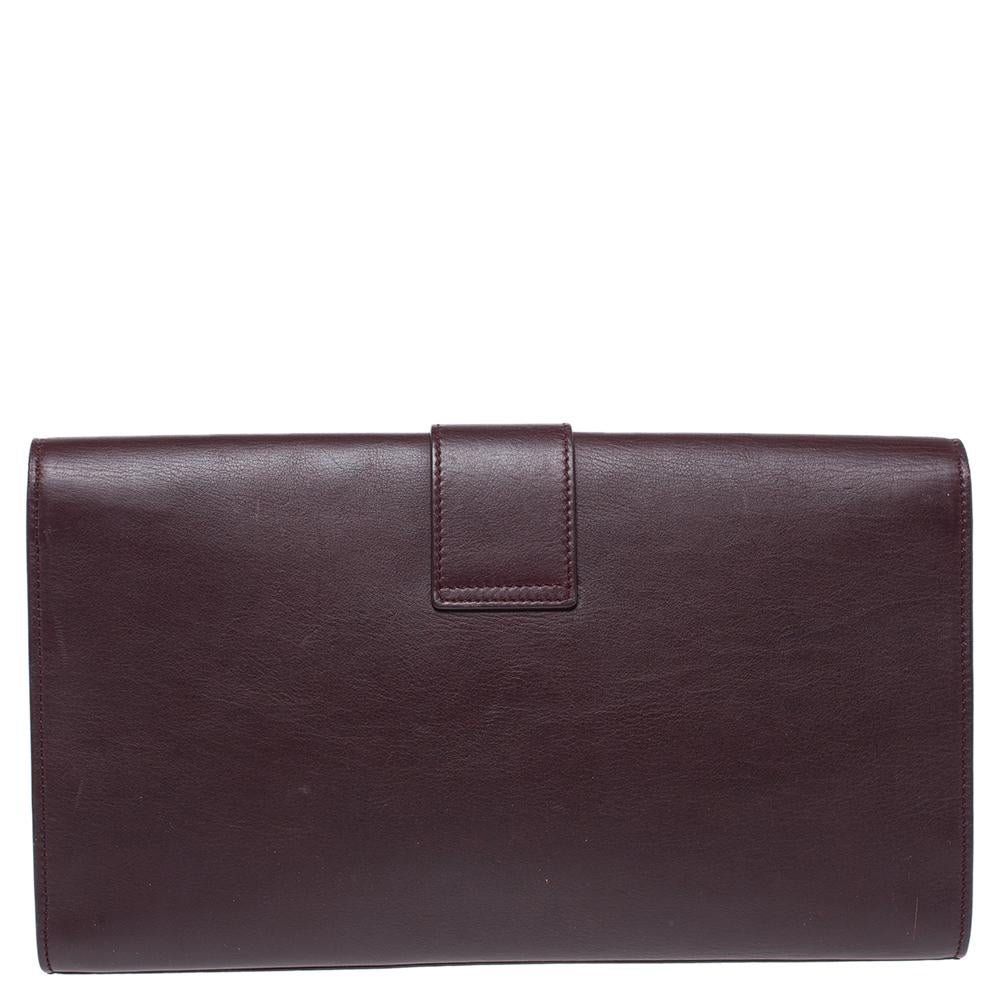 A simple design highlighted by a gold-tone Y on the front. The Ligne Y clutch by Saint Laurent is crafted from burgundy leather and designed in a flap style. It has a spacious suede interior where you can carry your cards, cash, and other