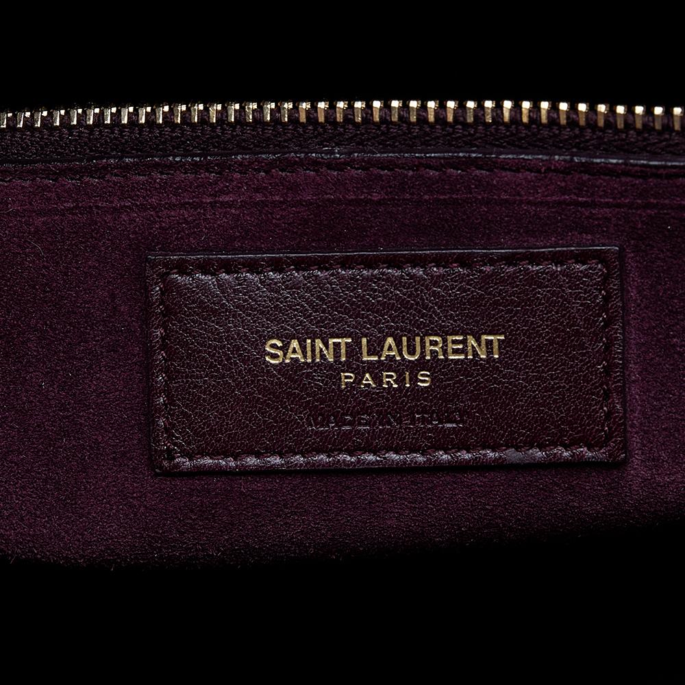 This Sac de Jour tote by Saint Laurent has a structure that simply spells sophistication. Crafted from burgundy leather, the bag is held by double top handles. The tote comes with a suede and fabric-lined interior with enough space to store your