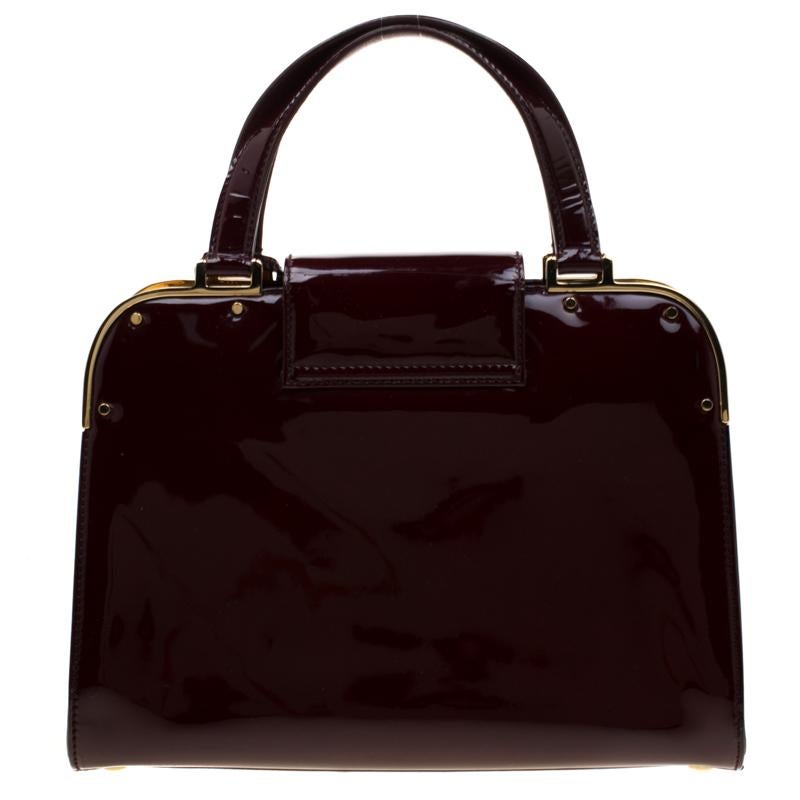 This bright and shiny small tote from Saint Laurent is exquisite. Its burgundy patent leather exterior is contrasted with gold-tone hardware. The exterior comes with a turn-lock closure, top handles, a clochette and metal ornamentation at the top