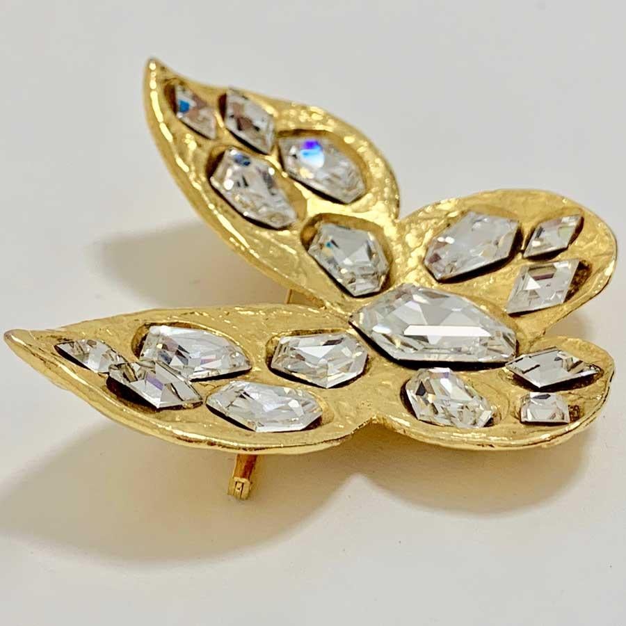 Superb butterfly-shaped brooch from YVES SAINT LAURENT. The brooch is made of hammered effect gold metal and set with more or less large white rhinestones.
Made in France.
This brooch is in perfect condition. The label of the brand is on the back of