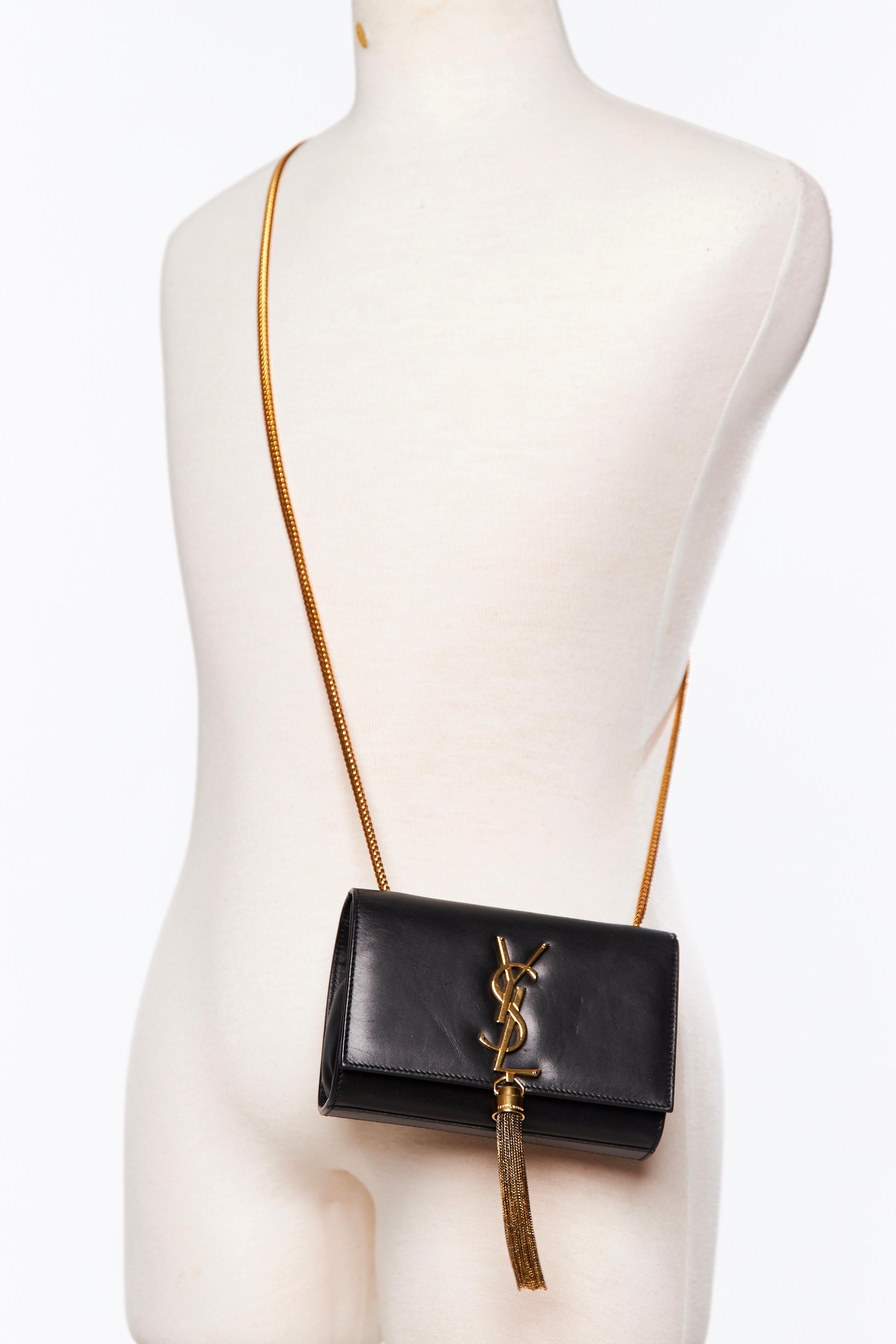 This shoulder bag is made of smooth calfskin leather in black. The bag features a gold chain link shoulder strap, a matching gold YSL logo, an accented chain link tassel, a crossover flap, magnetic snap closure and a black suede interior with a