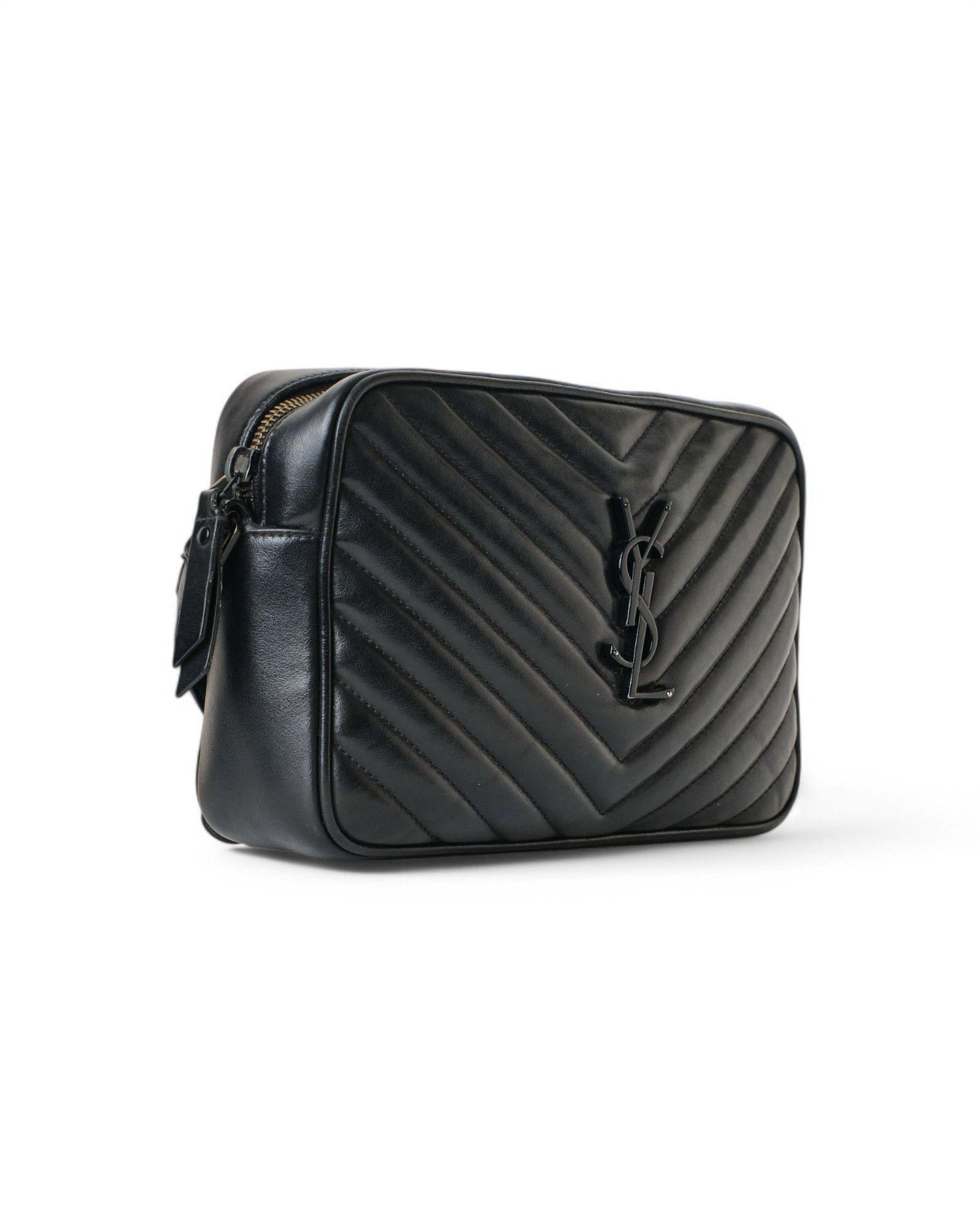 Saint Laurent signature bag, model Camera Bag, made of black quilted leather with black hardware details. Featuring a zippered top closure, the interior is lined with black fabric and offers a convenient open pocket, making it roomy enough for daily