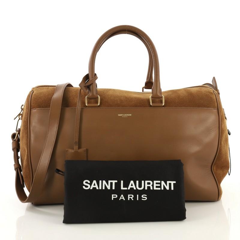 This Saint Laurent Classic Duffle Bag Leather with Suede 12, crafted from brown leather with suede, features dual rolled handles, protective base studs, and gold-tone hardware. Its two-way zip closure opens to a brown suede interior with side zip